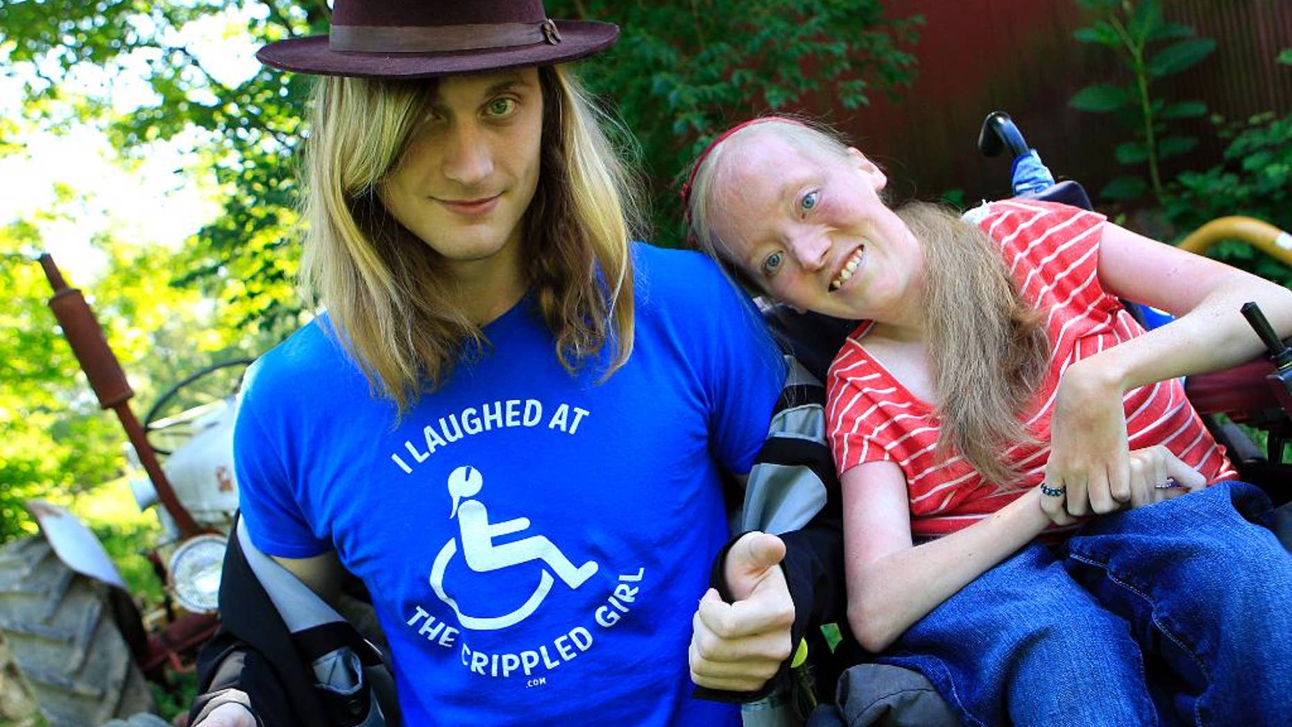FILE - In this June 13, 2012 file photo, Ally Bruener, right, poses for a photograph with friend Forest Thomer at her home in Alexandria, Ky. The comedy promoter, Thomer, who asked people if they wanted to laugh at a “crippled girl” in a wheelchair and then was arrested on a disorderly conduct charge has received $25,000 from the city to settle his federal lawsuit charging violation of his free-speech rights, the man’s attorney said Wednesday, Feb. 4, 2015. The question wasn’t intended to demean Bruener, but to promote her next comedy show and website. (AP Photo/The Cincinnati Enquirer, Cara Owsley, File) MANDATORY CREDIT; NO SALES