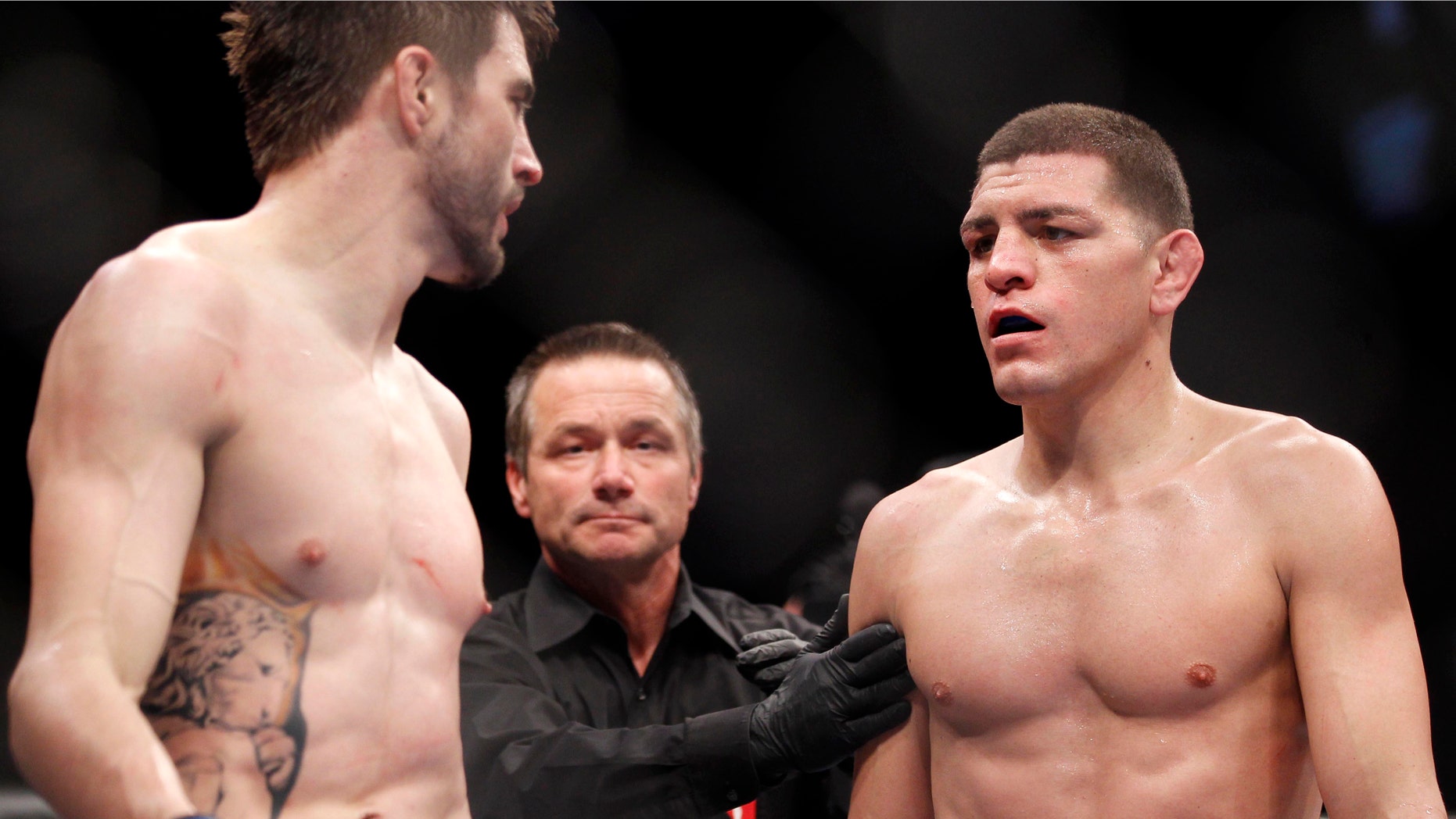 Carlos Condit, left, and Nick Diaz stare each other down as referee Steve Mazzagatti separates them at the end of the third round during their UFC interim welterweight mixed martial arts title match, Saturday, Feb. 4, 2012 at The Mandalay Bay Resort & Casino in Las Vegas. Condit won by unanimous decision. (AP Photo/Eric Jamison)