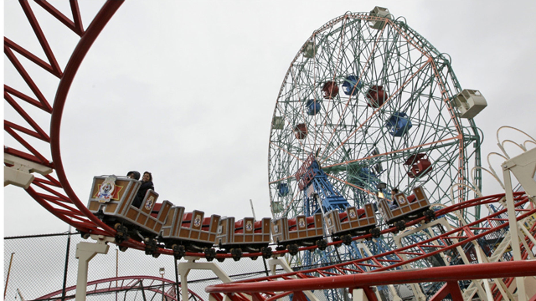 Visitors to Coney Island ride the Circus Coaster, foreground, and the Wonder Wheel, background, during opening day at Luna Park in Brooklyn, New York, Saturday, April 16, 2011. The opening of Luna Park and the Cyclone marked the beginning of the season in Coney Island.