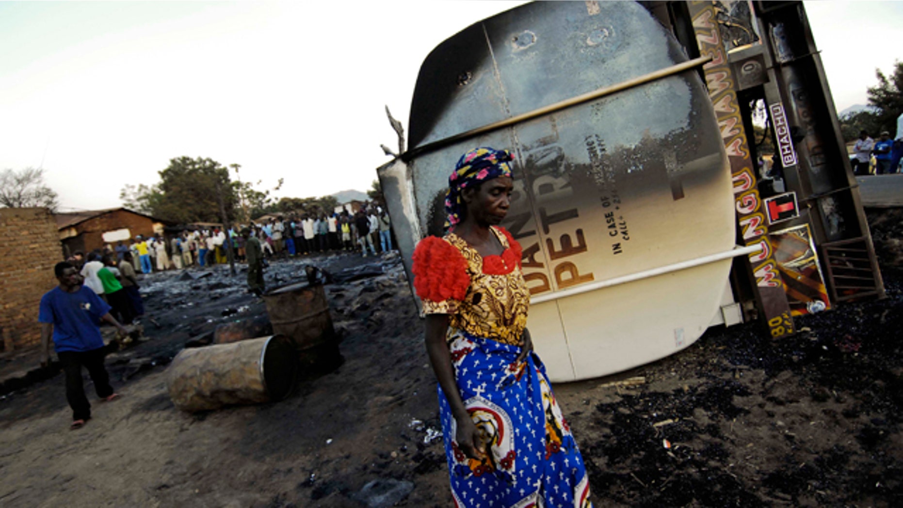 July 3: An inhabitant of the town of Sange, eastern Congo, walks past the burned out wreckage of a tanker truck involved in a accident Friday night.