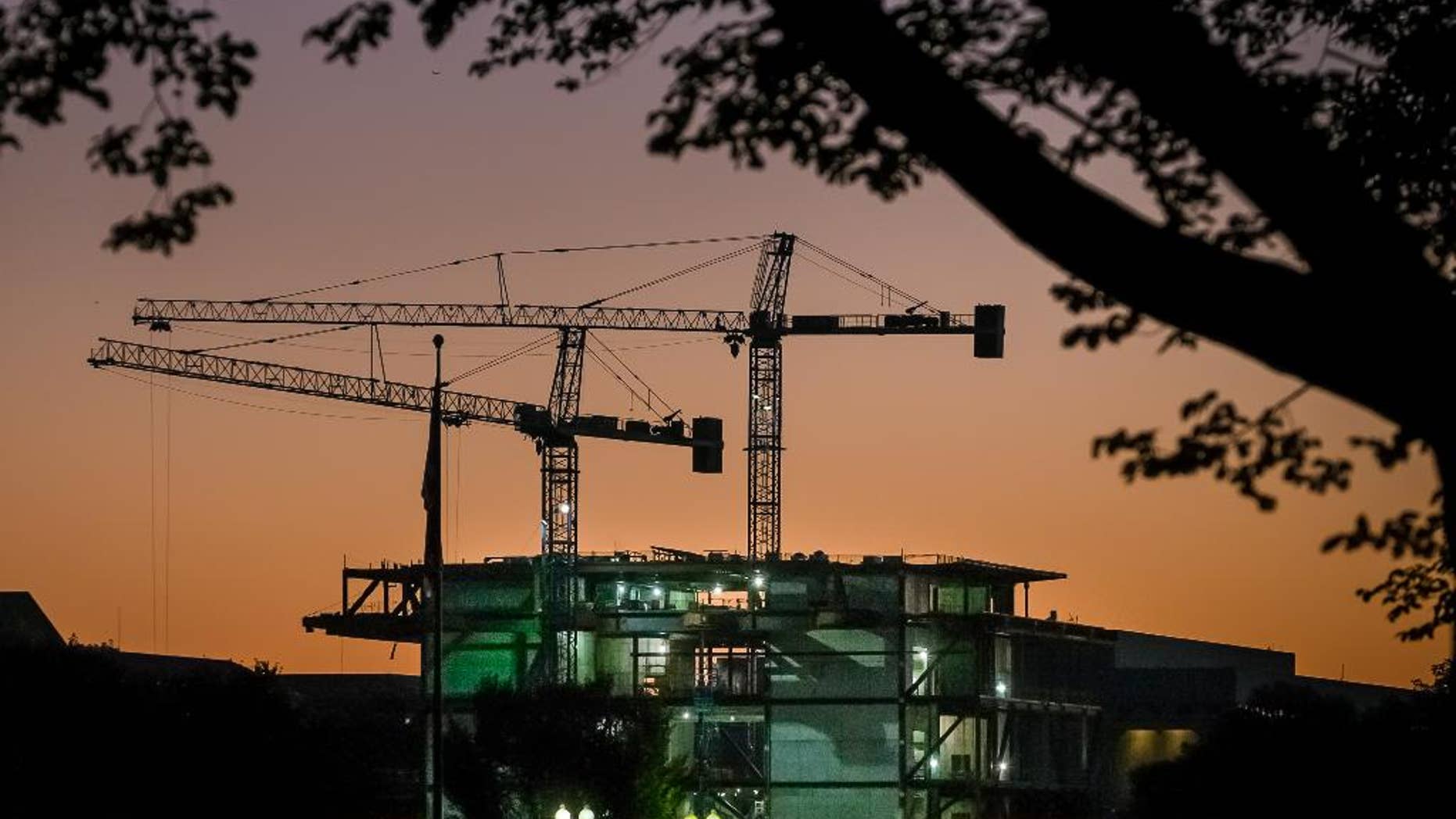 In this Oct. 8, 2014 photo, construction cranes are silhouetted against the early morning sky as work continues on Smithsonian's new National Museum of African American History and Culture in Washington. The Commerce Department releases construction spending for September on Monday, Nov. 3, 2014. (AP Photo/J. David Ake)