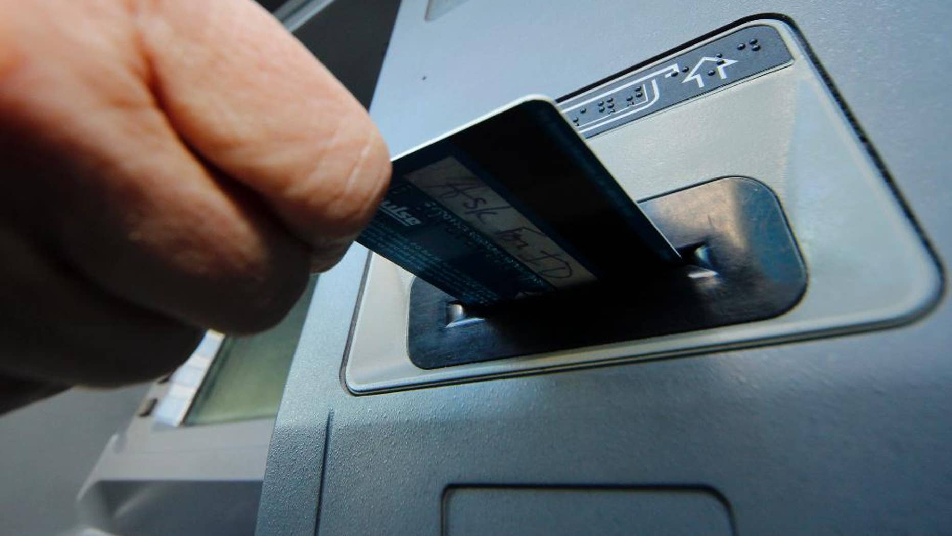 FILE - In this Saturday, Jan. 5, 2013 photo, a person demonstrates using a credit card in an ATM in Pittsburgh. The Federal Reserve on Monday, April 7, 2014 will release a report on how much consumers borrowed in February. (AP Photo/Gene J. Puskar, File)