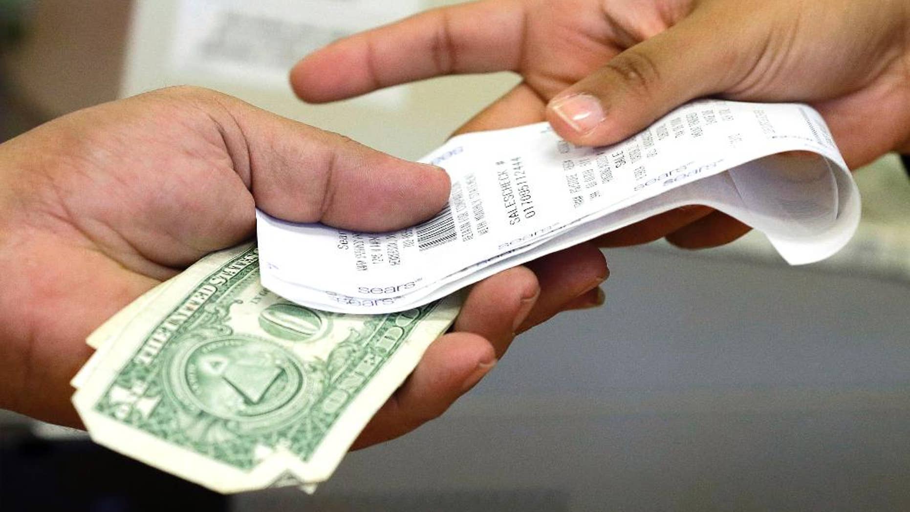 FILE - In this Friday, Nov. 23, 2012 file photo, a cashier hands a customer his change and receipt during a transaction at a Sears store, in Henderson, Nev. The University of Michigan issues its index of consumer sentiment for June, 2014 on Friday, June 27, 2014. (AP Photo/Julie Jacobson, File)