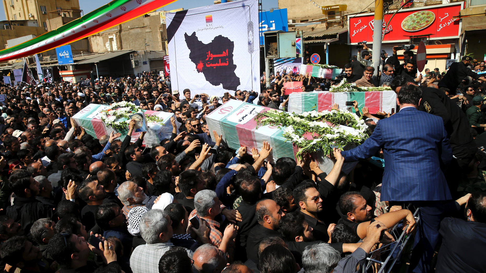 Mourners carry flag-draped caskets during a mass funeral for victims of Saturday's terror attack on a military parade, in the southwestern city of Ahvaz, Iran, Monday, Sept. 24, 2018. Thousands of mourners gathered at the Sarallah Mosque on Ahvaz's Taleghani junction, carrying caskets in the sweltering heat. (AP Photo/Ebrahim Noroozi)