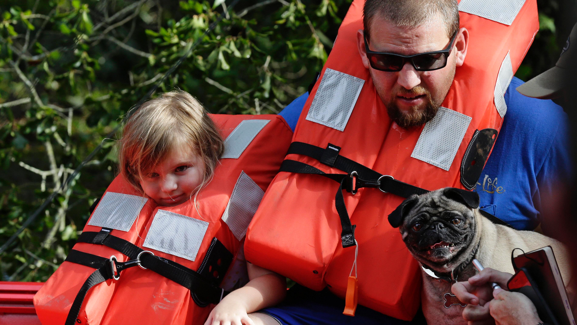 Brent Lamb, right, and his daughter Laci, 4, are removed from a flooded neighborhood by members of the U.S. Coast Guard Shallow Water Rescue Team in Lumberton, N.C., Monday, Sept. 17, 2018, following flooding from Hurricane Florence. (AP Photo/Gerry Broome)