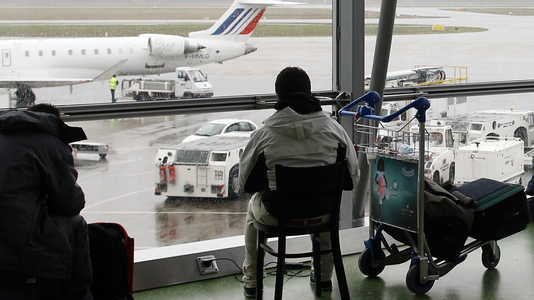 FILE - In this Dec.17, 2011 file photo, a passenger waits for his flight during a strike at Lyon-Saint Exupery airport, central France. Authorities say police have arrested a man who rammed his car through two glass doors at Lyon's international airport and sped onto the runway. (AP Photo/Laurent Cipriani, File)