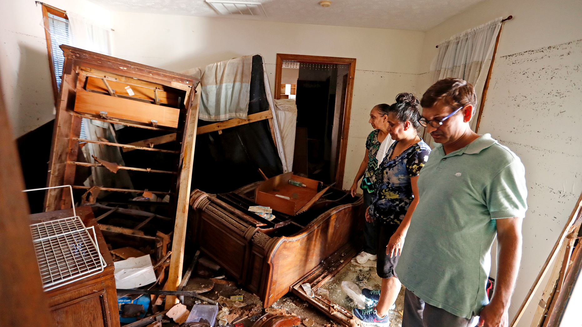 In this Wednesday, Sept. 19, 2018 photo, Smita Depani, center, stands in the apartment she lived in while surveying the damage with her brother-in-law Jayanti Depani, right, and sister-in-law Puspa Manvar in the Starlite Motel they own which was destroyed in the flooding from Hurricane Florence in Spring Lake, N.C. (AP Photo/David Goldman)