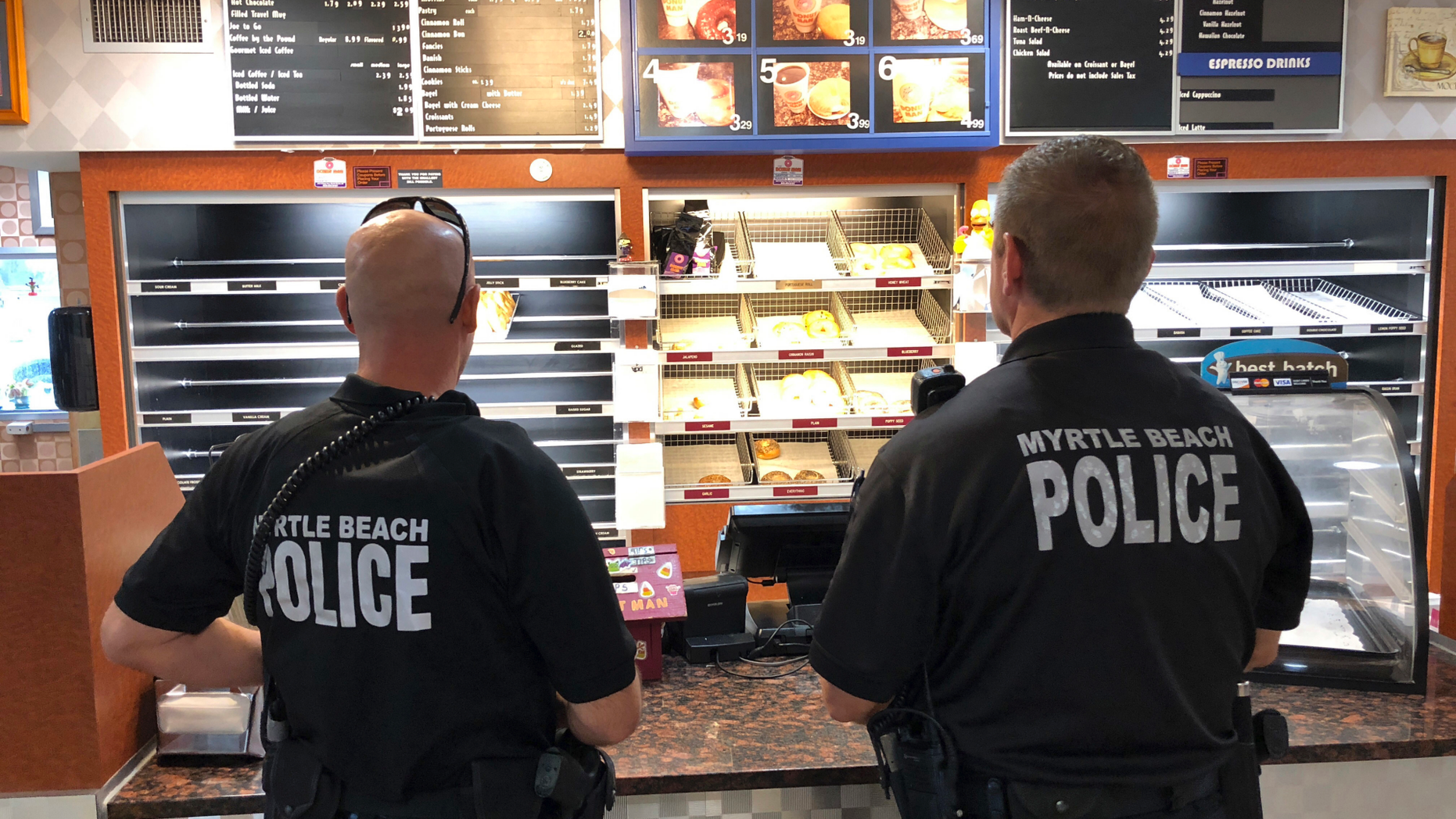 Two police officers get ready to order at Joseph Santos' Donut Man restaurant in Myrtle Beach, S.C., on Friday, Sept. 14, 2018. Santos says he keeps his restaurant open to feed police officers, firefighters and others who have to work no matter what. (AP Photo/Jeffrey Collins)