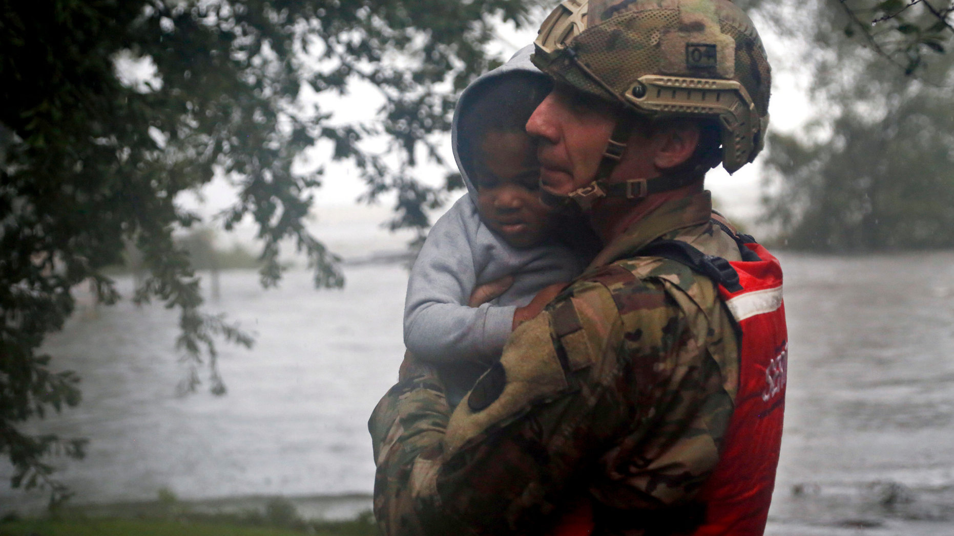 Rescue team member Sgt. Nick Muhar, from the North Carolina National Guard 1/120th battalion, evacuates a young child as the rising floodwaters from Hurricane Florence threatens his home in New Bern, N.C., on Friday, Sept. 14, 2018. (AP Photo/Chris Seward)