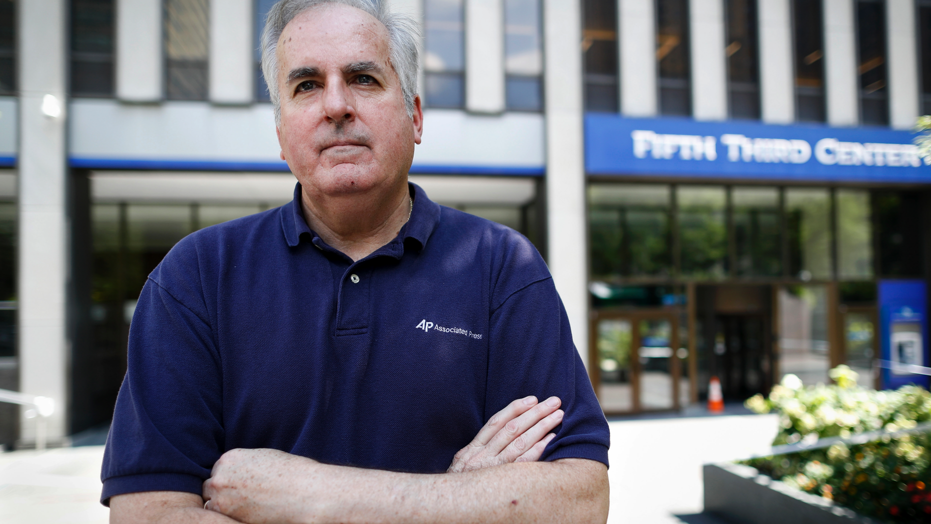 In this Friday, Sept. 14, 2018 photo, Associated Press senior correspondent Dan Sewell poses for a photograph outside the scene of a shooting that occurred the previous week at Fountain Square, in Cincinnati. "Over four decades with The Associated Press, I have many times thrown clothes into a bag, withdrawn a wad of cash, and stuffed my laptop with notebooks and pens before rushing by car or plane to a terrible event in someone else's hometown, state or country," said Sewell. "This time, it was in my town." (AP Photo/John Minchillo)