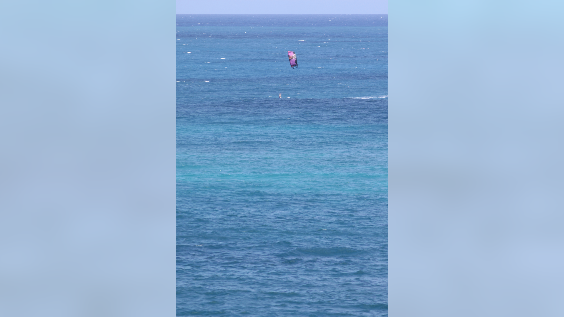 A kite surfer rides a wave as Tropical Storm Olivia approaches Hawaii, Tuesday, Sept. 11, 2018, near Honolulu. The National Weather Service says the storm could dump as much as 20 inches of rain on some parts of the islands as it hits late Tuesday and into Wednesday. (AP Photo/Caleb Jones)