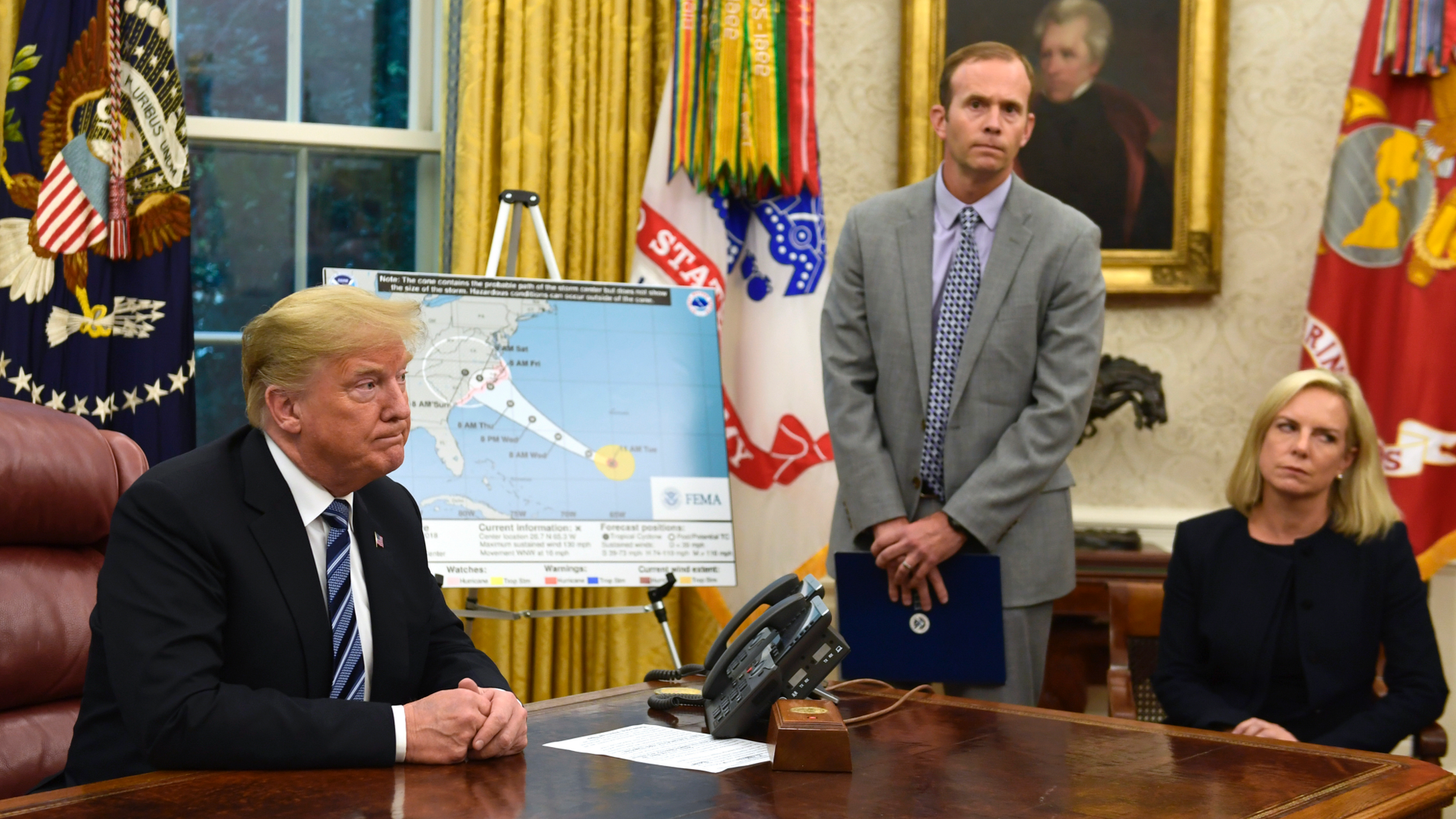 President Donald Trump, left, listens to a reporters question as FEMA Administrator Brock Long, center, and Homeland Security Secretary Kirstjen Nielsen, right, listen during a briefing on Hurricane Florence in the Oval Office of the White House in Washington, Tuesday, Sept. 11, 2018. (AP Photo/Susan Walsh)