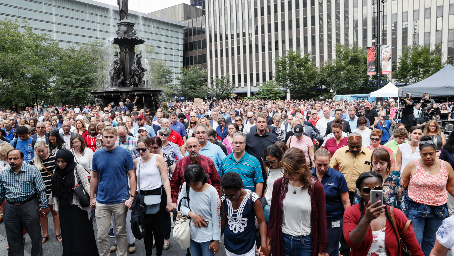 Mourners hold hands during a vigil Friday, Sept. 7, 2018 in Cincinnati's Fountain Square near the site of Thursday's fatal shooting. Suspect Omar Enrique Santa Perez was killed by police officers. (AP Photo/John Minchillo)
