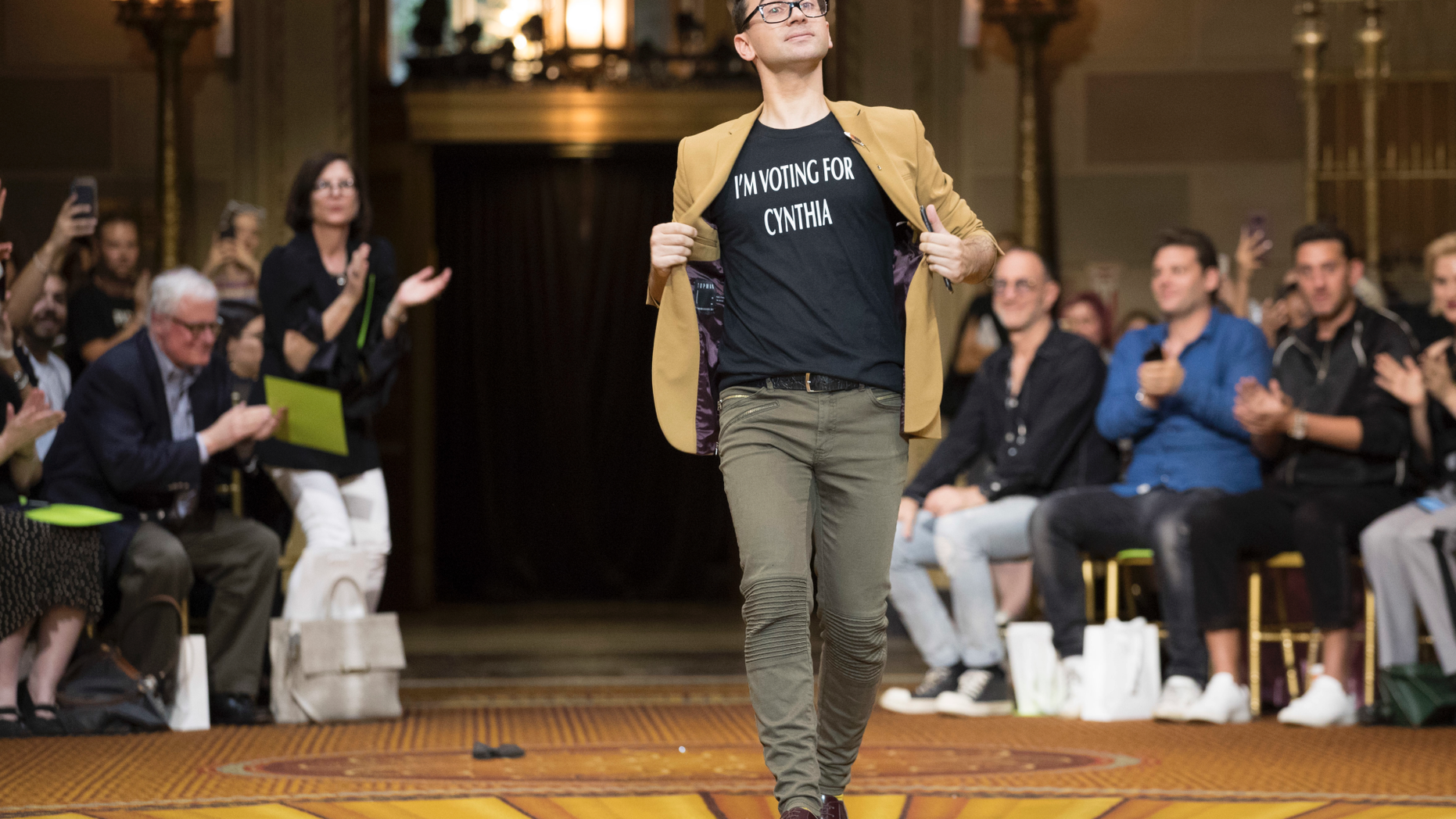 Christian Siriano wears a T-shirt supporting Democratic New York gubernatorial candidate Cynthia Nixon as he walks onto the runway after his spring 2019 collection was modeled during Fashion Week in New York, Saturday, Sept. 8, 2018. (AP Photo/Mary Altaffer)