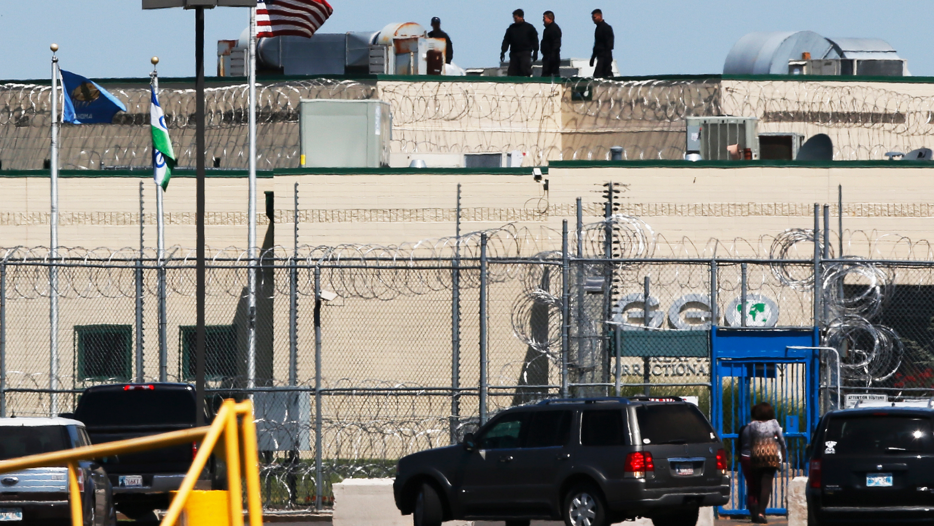 People walk on the roof above the front gate of the Great Plains Correctional Facility in Hinton, Okla, Monday, July 10, 2017.