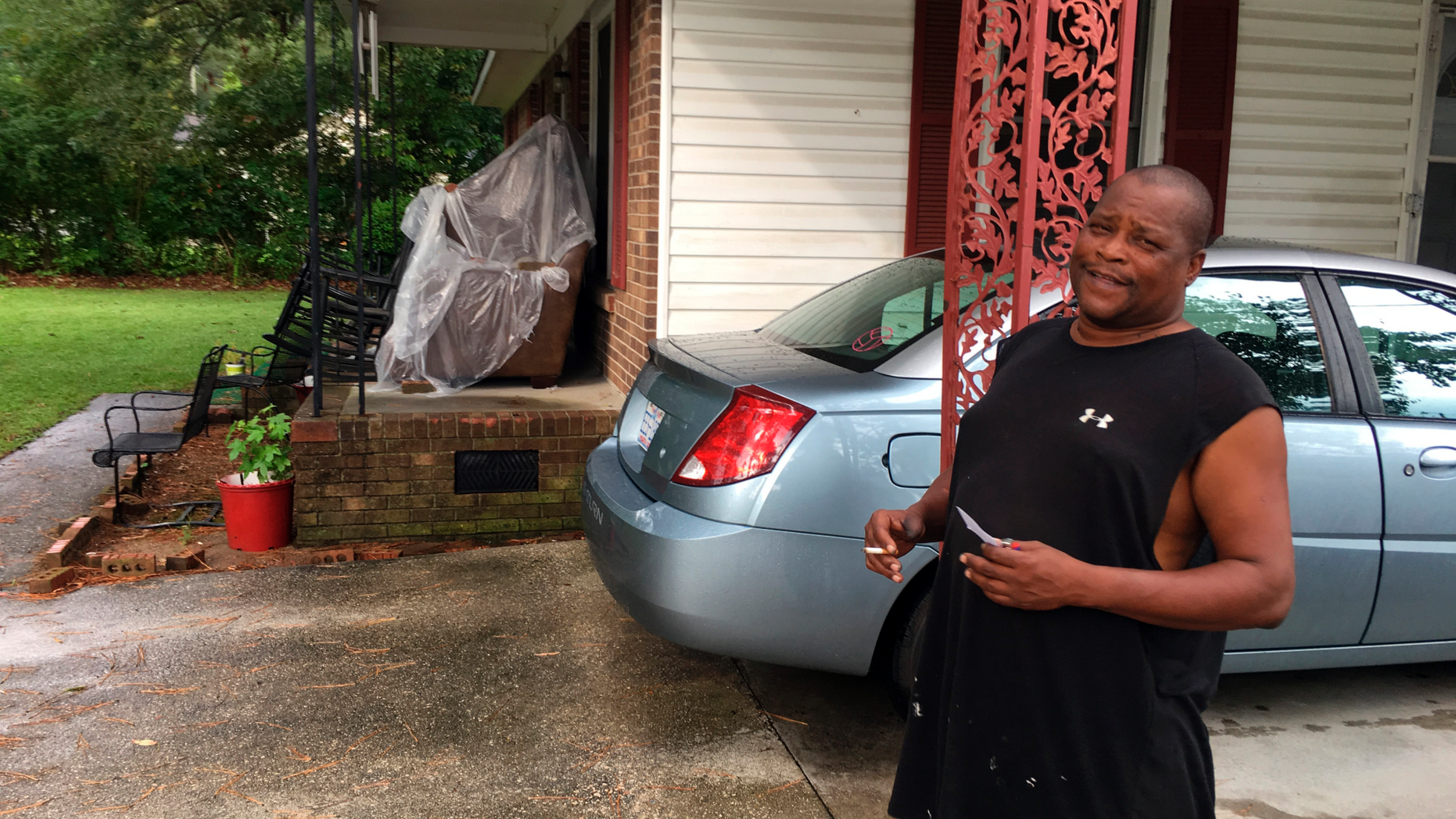 James Howell Jr. sizes up how to protect his home Tuesday, Sept. 11, 2018, in Princeville, N. C., from the approaching Hurricane Florence. The house was damaged by Hurricane Matthew in 2016. Howell said the furniture on his porch is there because he had to go out and rebuild the living room. (AP Photo/Emery Dalesio)