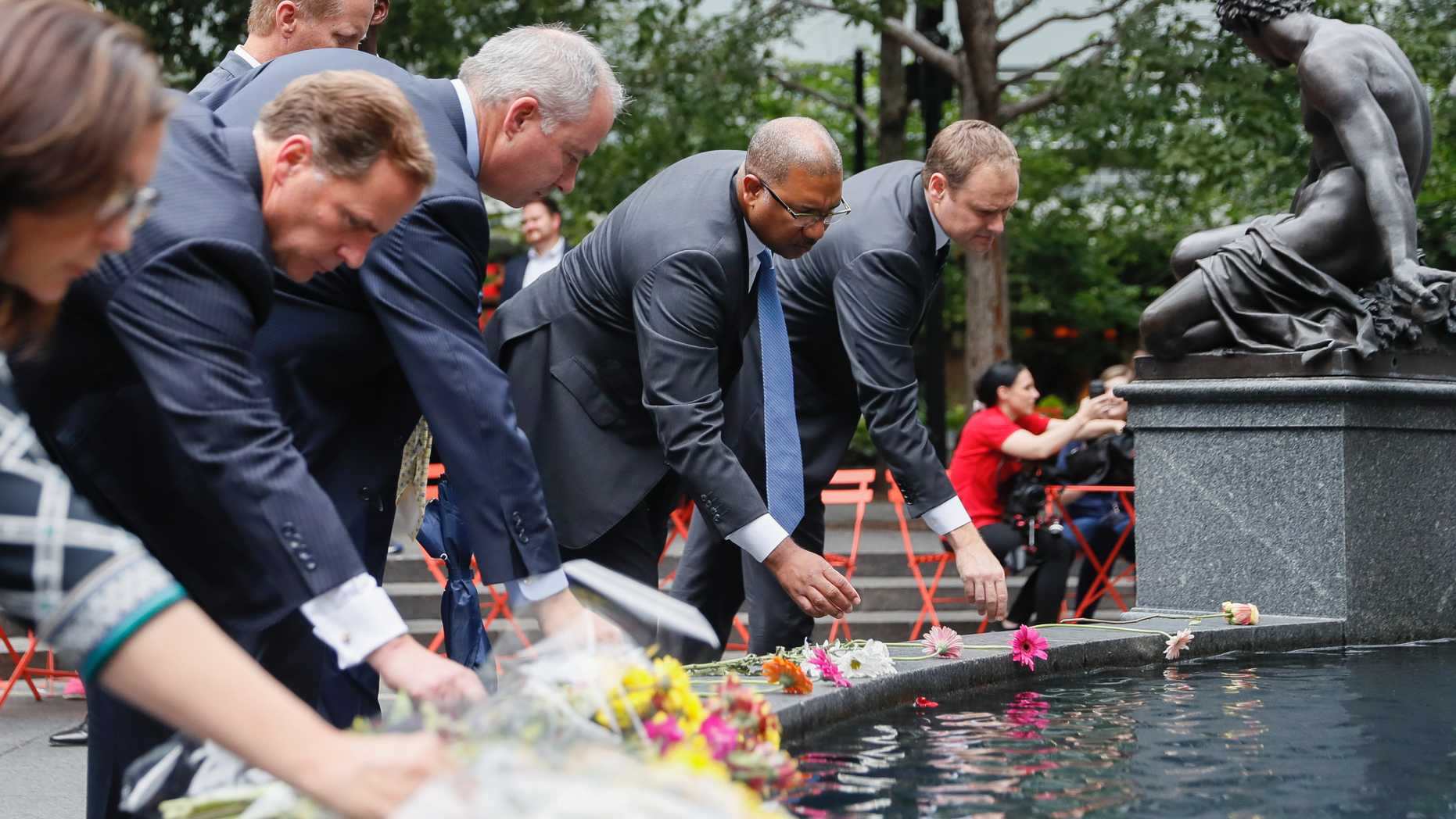 Mourners place flowers at the fountain edge before a vigil in Fountain Square where a shooting took place the previous day that claimed the lives of three civilians, Friday, Sept. 7, 2018, in Cincinnati. Suspect Omar Enrique Santa Perez entered the Fifth Third Center and began firing before being neutralized by police officers. (AP Photo/John Minchillo)