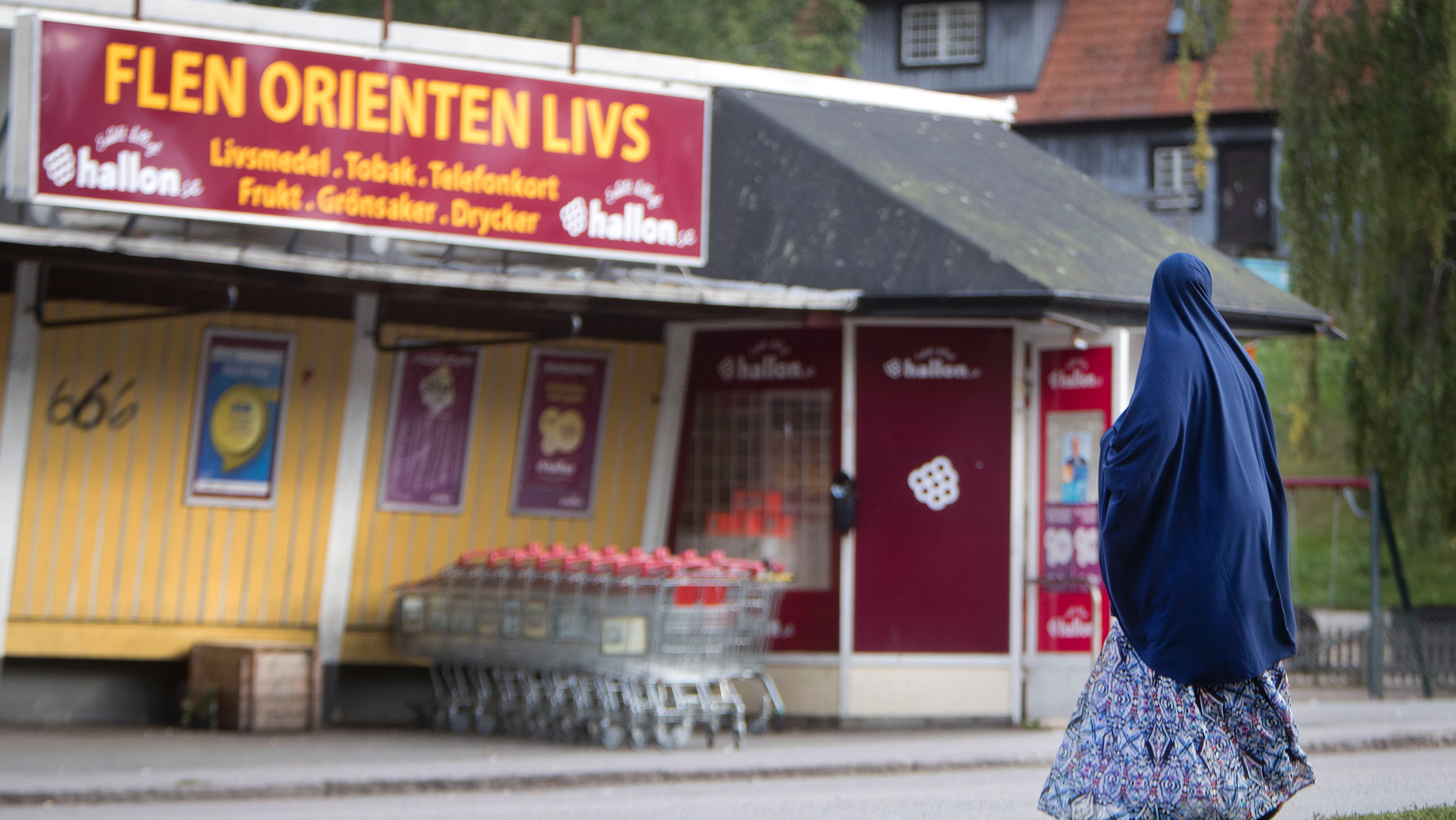 In this Aug. 30, 2018 photo a migrant woman stands in front of an orient supermarket in Flen, some 100 km west of Stockholm, Sweden. The town has welcomed so many asylum seekers in recent years that they now make up about a fourth of the population. (AP Photo/Michael Probst)