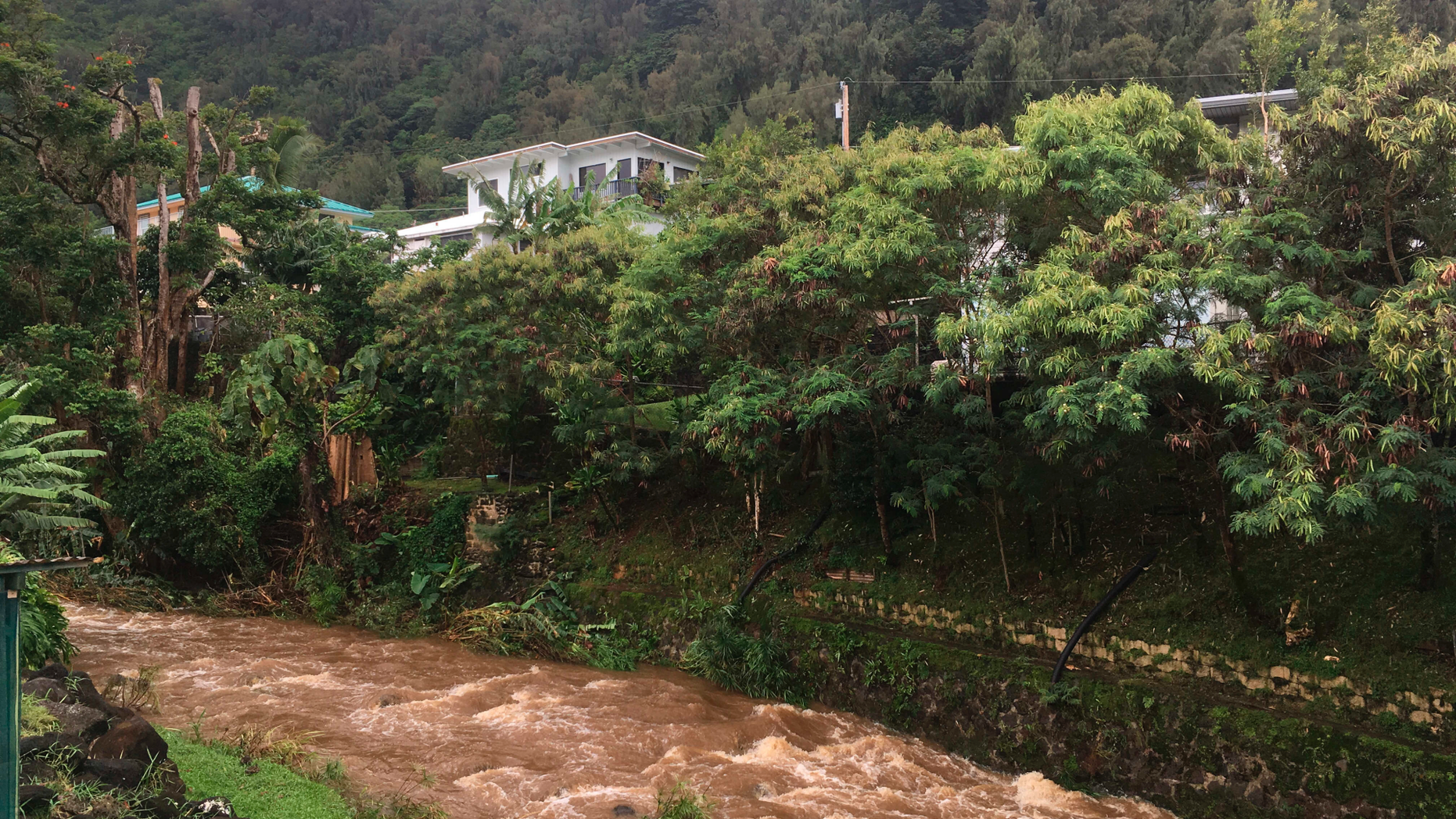 Water rushes through a spillway in a neighborhood below the Nuuanu Dam in Honolulu on Thursday, Sept. 13, 2018. Honolulu officials say they may need to evacuate 10,000 people from a residential neighborhood if water in the reservoir continues to rise after heavy rains from a tropical storm. (AP Photo/Caleb Jones)