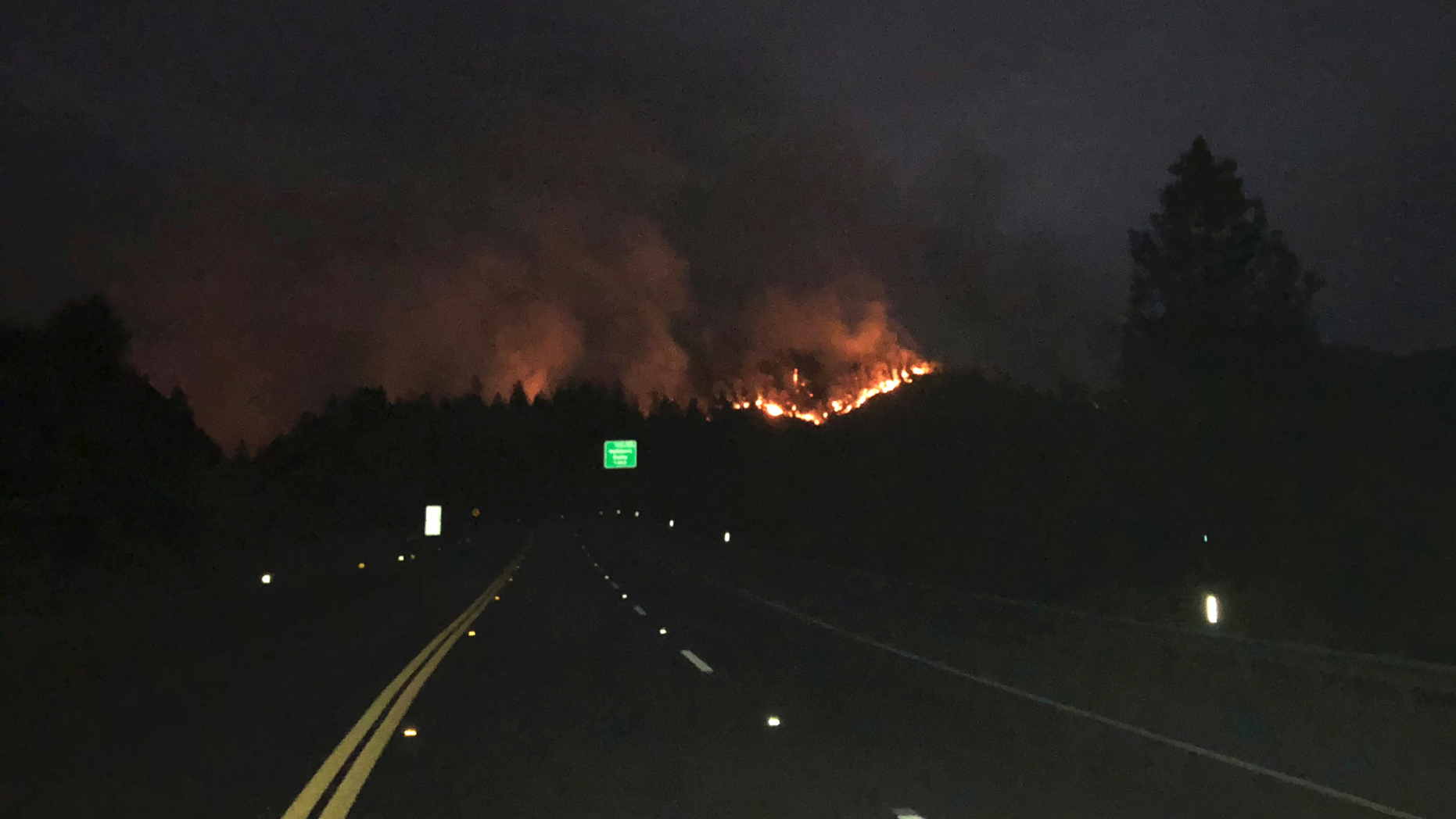 In this photo provided by the California Department of Transportation, lanes are closed on northbound Interstate 5 with the Delta Fire burning in the background Friday, Sept. 7, 2018, near Lakehead, Calif. A stretch of a major highway near the California-Oregon border will remain closed through the weekend as crews try to tame a roaring wildfire burning on both sides of the north-south route, authorities announced Friday. The blaze that shut down Interstate 5 on Wednesday was still burning out of control, said Denise Yergenson, a spokeswoman for the California Department of Transportation. (Joe Spini/California Department of Transportation via AP)