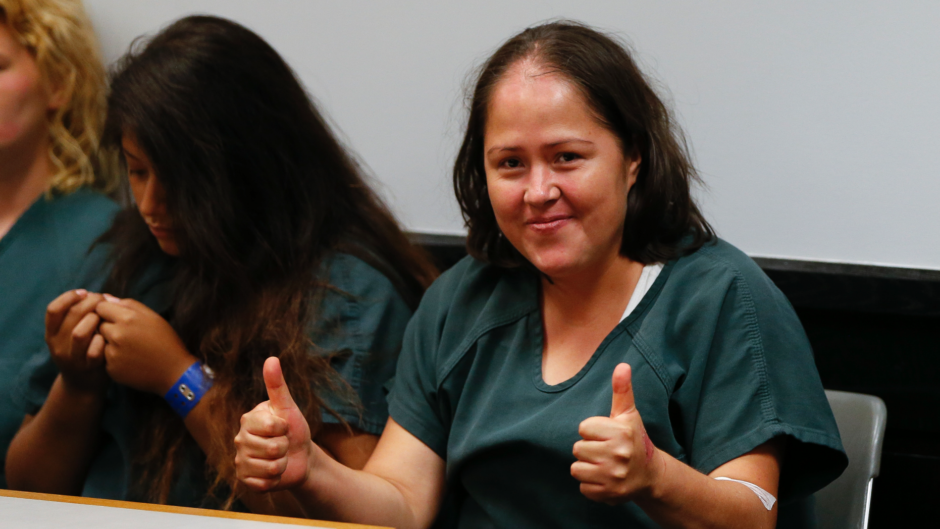 Isabel Martinez, the woman accused of fatally stabbing her four children and husband, smiles and gives two thumbs up at her court hearing.