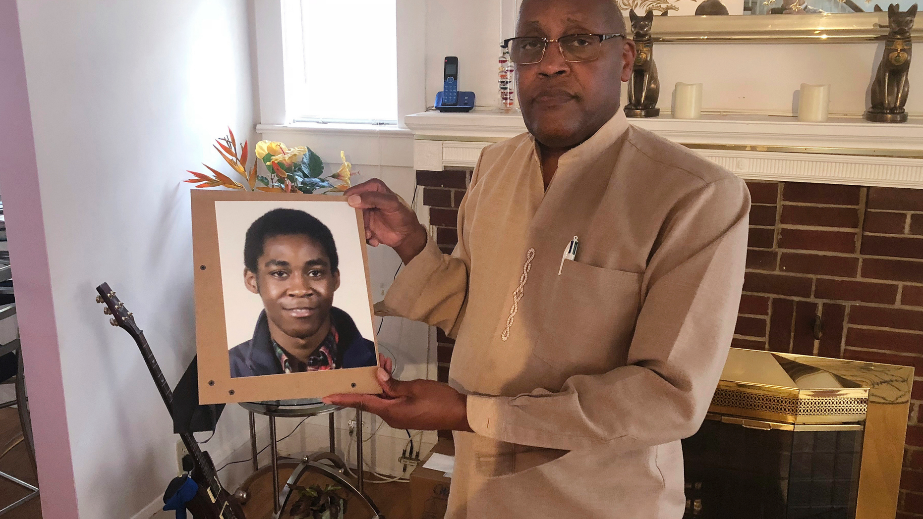 FILE - In this Sept. 5, 2018 file photo, Dia Khafra, father of Askia Khafra, holds a photo of his son in his Silver Springs, Md., home. The parents of 21-year-old Askia Khafra sued 27-year-old Daniel Beckwitt and his father on Monday, Sept. 10, 2018, the anniversary of the fire that killed Khafra in the basement of the Beckwitts' house in Bethesda, Maryland. (AP Photo/Michael Kunzelman)