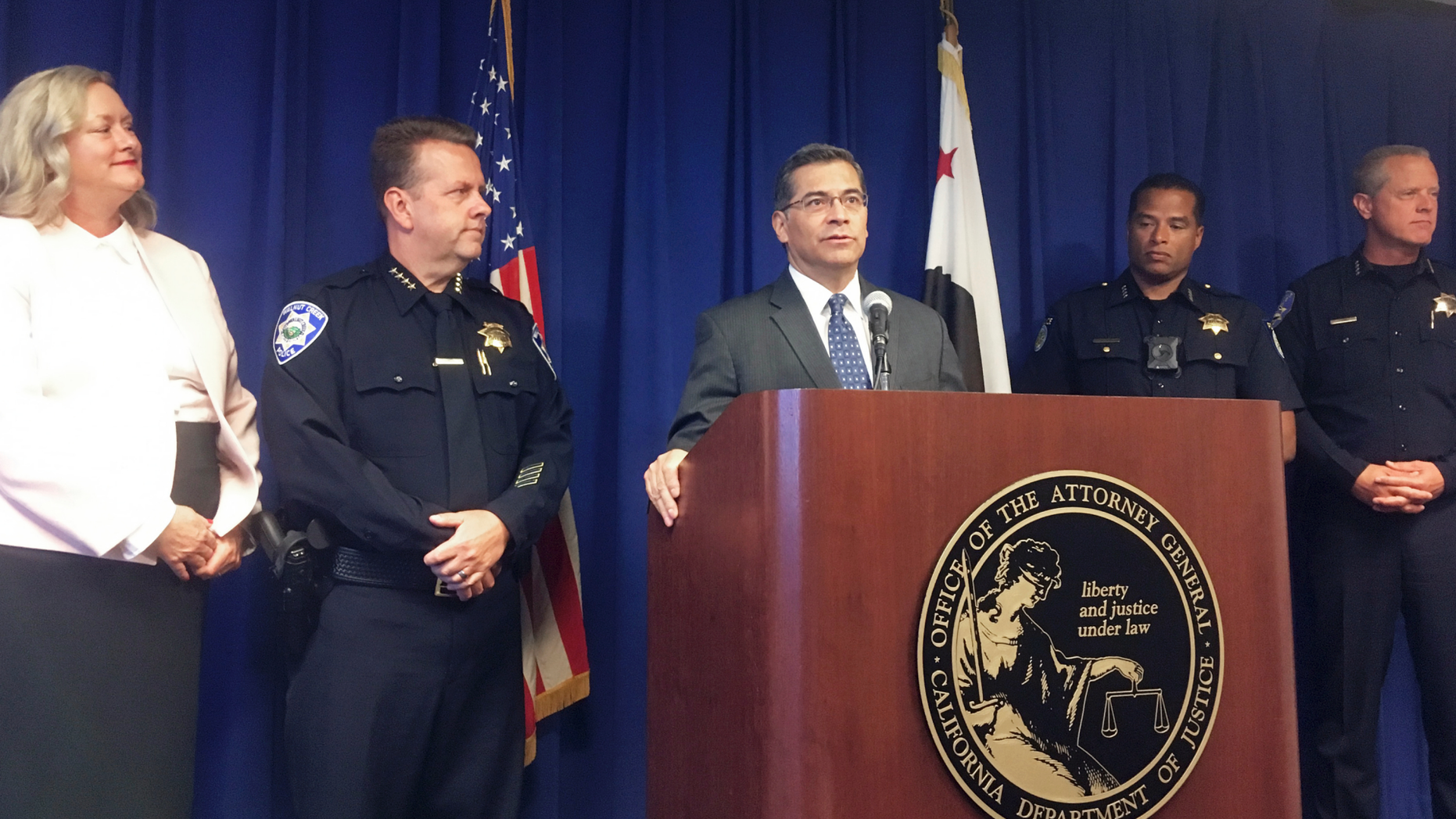 California Attorney General, Xavier Becerra, at podium, and other officials announce indictments of 32 members of purported street gangs on charges of stealing more than $1 million using an unusually sophisticated credit card fraud, at a news conference in Sacramento, Calif., Monday, Sept. 10, 2018. From left are Deputy Attorney General Tawnya Austin, who heads the attorney general's e-crimes unit; Walnut Creek Police Chief Tom Chaplin; Becerra; Sacramento Police Chief Daniel Hahn; and Vacaville Police Chief John Carli. Authorities said Monday that the BullyBoys and the CoCo Boys street gangs defrauded hundreds of victims across Northern California by breaking into dozens of medical and dental offices to steal credit card terminals and patient records. (AP Photo/Don Thompson)