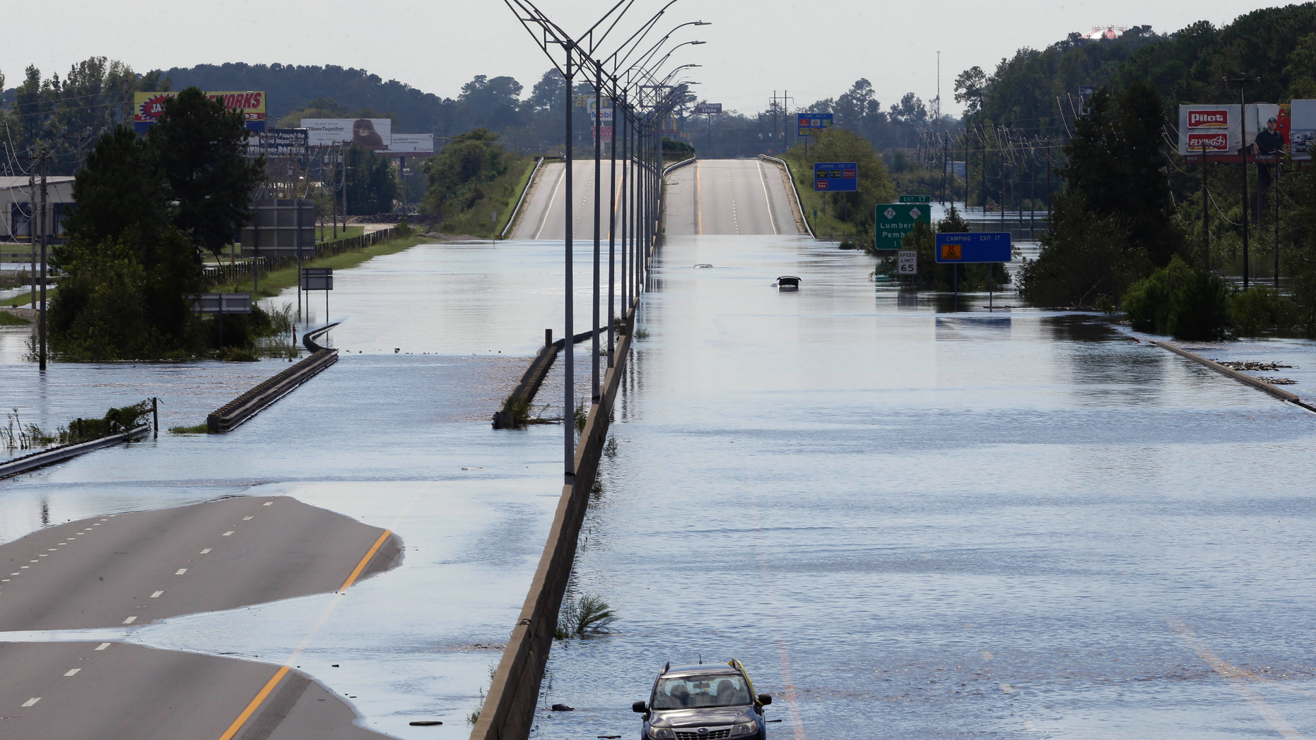 FILE- In this Monday, Sept. 17, 2018, file photo flooded vehicles sit on a closed section of Interstate 95 in Lumberton, N.C., where the Lumber river overflowed following flooding from Hurricane Florence. Navigation apps like Waze are trying to help motorists avoid hurricane flooding, but local authorities say people shouldn’t rely on them. (AP Photo/Gerry Broome, File)