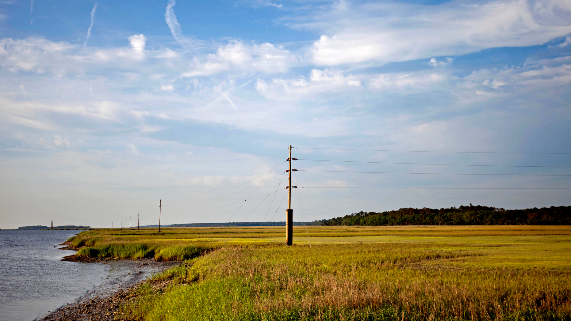 FILE - In this May 16, 2013, file photo, a utility pole stands in the middle of a marsh at sunset on Sapelo Island, Ga., a Gullah-Geechee community. A tight-knit community of slave descendants on the South Carolina coast is used to riding out big storms, from a storm that killed an estimated 2,000 people in 1893 to Tropical Storm Irma last year. (AP Photo/David Goldman, File)