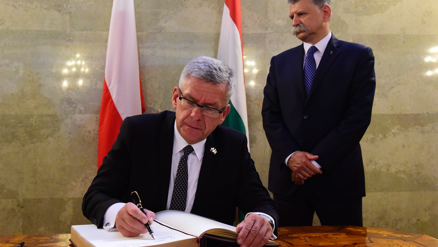 FILE - In this Monday, Sept. 12, 2016 file photo, Speaker of the Polish Senate Stanislaw Karczewski, left, signs the guest book after his meeting with Speaker of the Hungarian Parliament Laszlo Kover, right, in the Hungarian Parliament in Budapest, Hungary. The European Union said Monday, Sept. 24, 2018 it has decided to take Poland to the bloc’s top court over the overhaul of the country’s judicial system and also ask the European Court of Justice to suspend a recent law on Supreme Court judges. The EU’s executive Commission has been increasingly critical of Poland’s judicial reform under a right-wing government. Senate Speaker Stanislaw Karczewski said the government had expected the Commission’s move but will keep repeating its “strong, legal and essential” arguments.(Tamas Kovacs/MTI via AP, file)