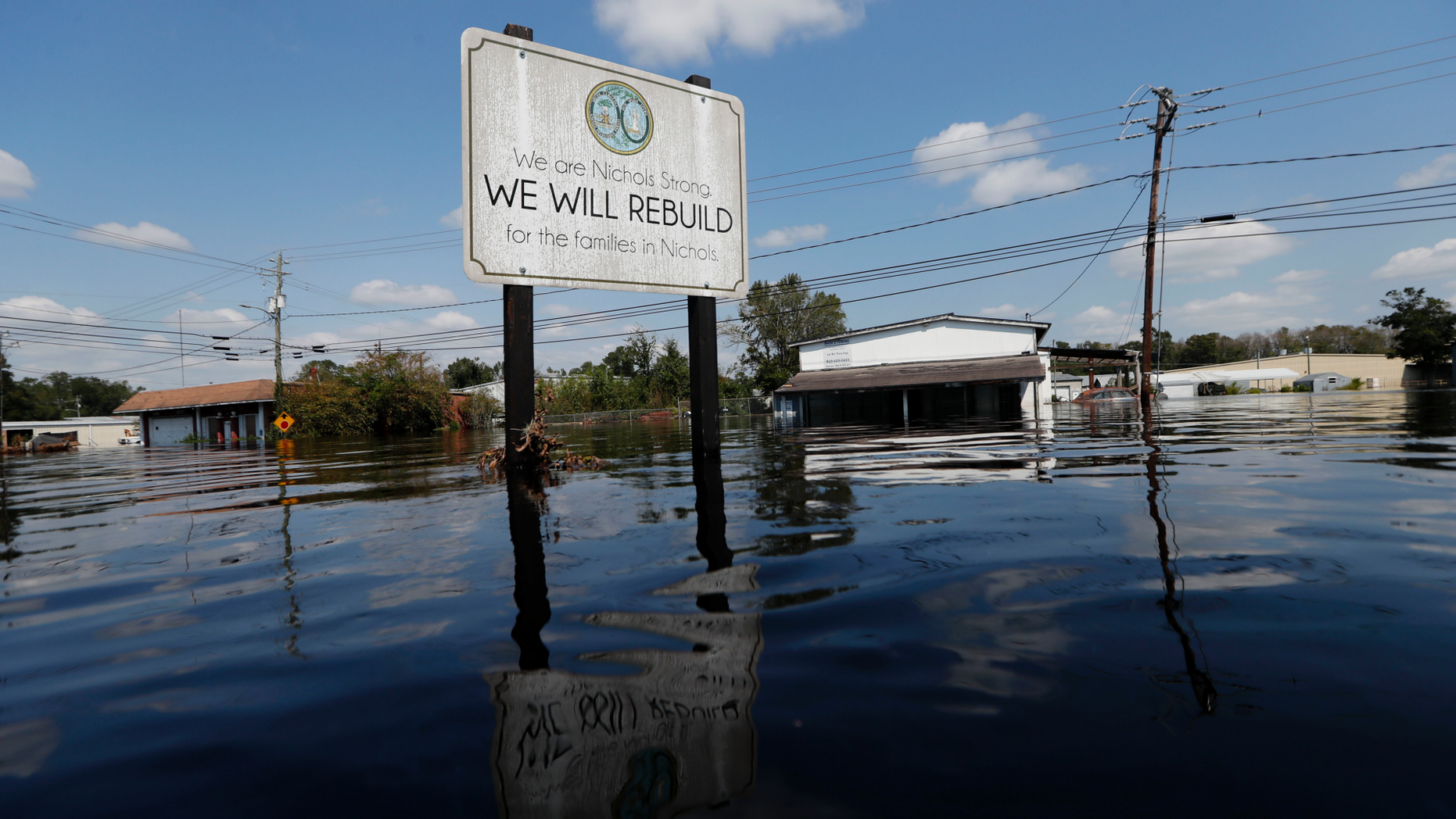 A sign commemorating the rebuilding of the town of Nichols, which was flooded two years earlier from Hurricane Matthew, stands in floodwaters in the aftermath of Hurricane Florence in Nichols, S.C., Friday, Sept. 21, 2018. Virtually the entire town is once again flooded and inaccessible except by boat. (AP Photo/Gerald Herbert)