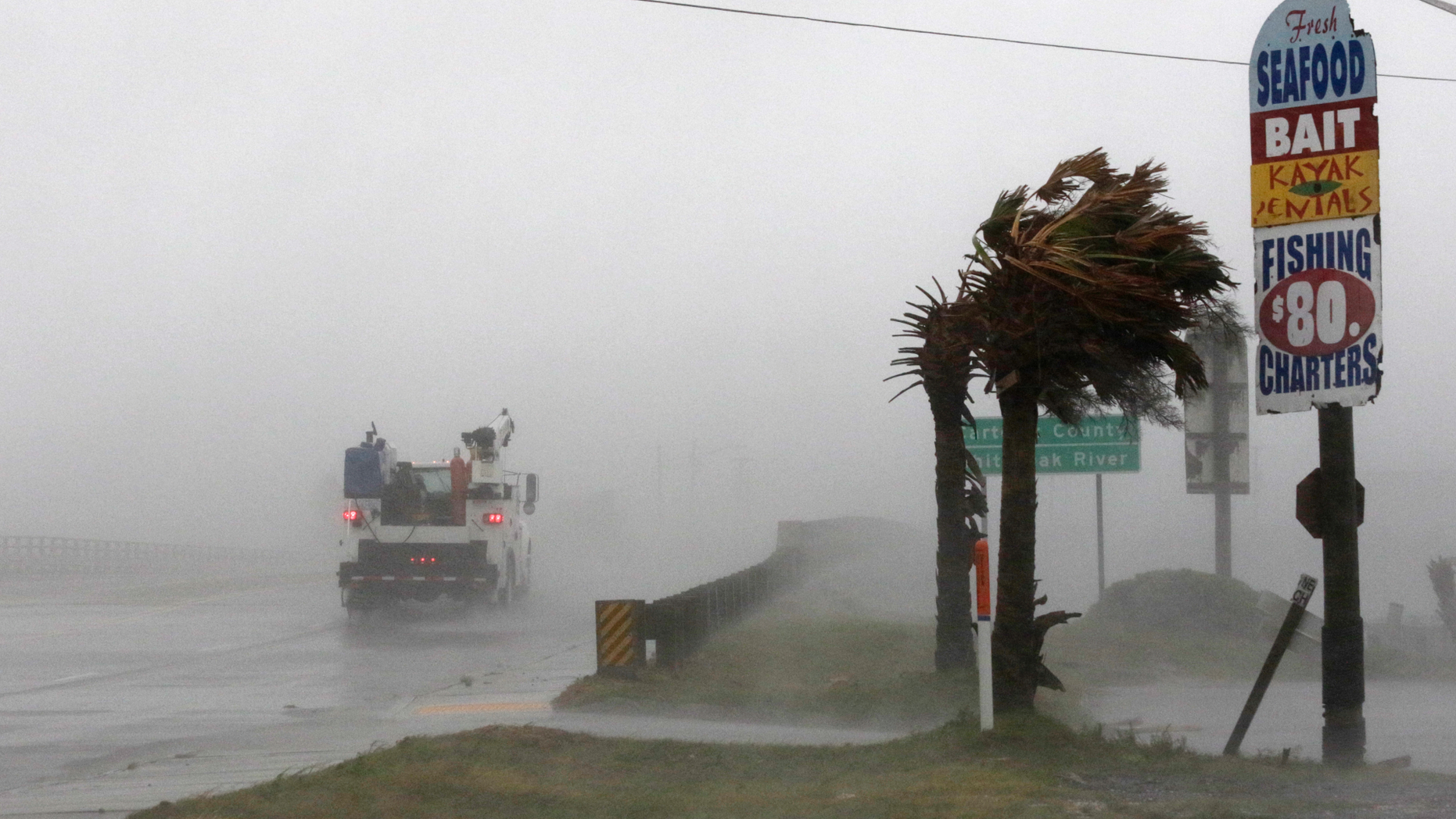 A work truck drives on Hwy 24 as the wind from Hurricane Florence blows palm trees in Swansboro N.C., Thursday, Sept. 13, 2018. (AP Photo/Tom Copeland)