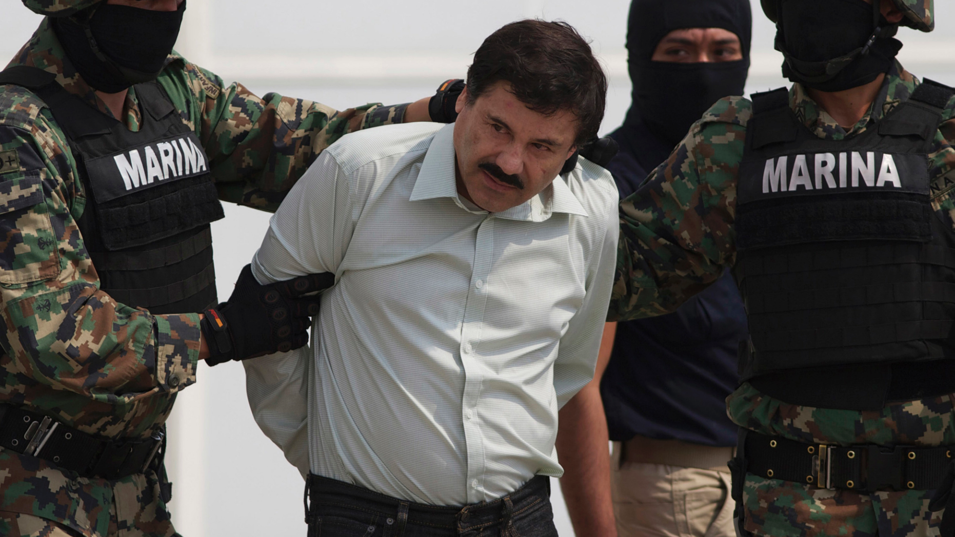 FILE - In this Feb. 22, 2014, file photo, Joaquin "El Chapo" Guzman is escorted to a helicopter in handcuffs by Mexican navy marines at a navy hanger in Mexico City, Mexico. A U.S. judge has rejected a request to put off the trial of notorious Mexican drug lord Guzman. Lawyers for Guzman told Judge Brian Cogan at a hearing Thursday, Sept. 20, 2018, that they needed more time to review a mountain of evidence in the drug-trafficking case. (AP Photo/Eduardo Verdugo, File)