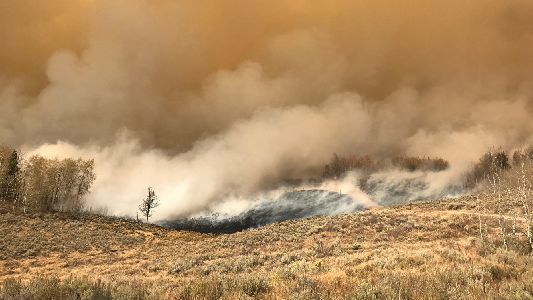 In this Sunday, Sept. 23, 2018, photo provided by Bill Winney, flames approach his home near Bondurant, Wyo. Winney, who saw the immense wildfire raging his way, said he was prepared for the worst - and glad he defied evacuation orders so he could defend his home with just a sprinkler and garden hose. Most firefighters would say Winney's decision is a good example of what not to do when a wildfire is approaching. Better to get out rather than risk your life in an attempt to protect property, fire information officer Susan Garner said. (Bill Winney via AP)