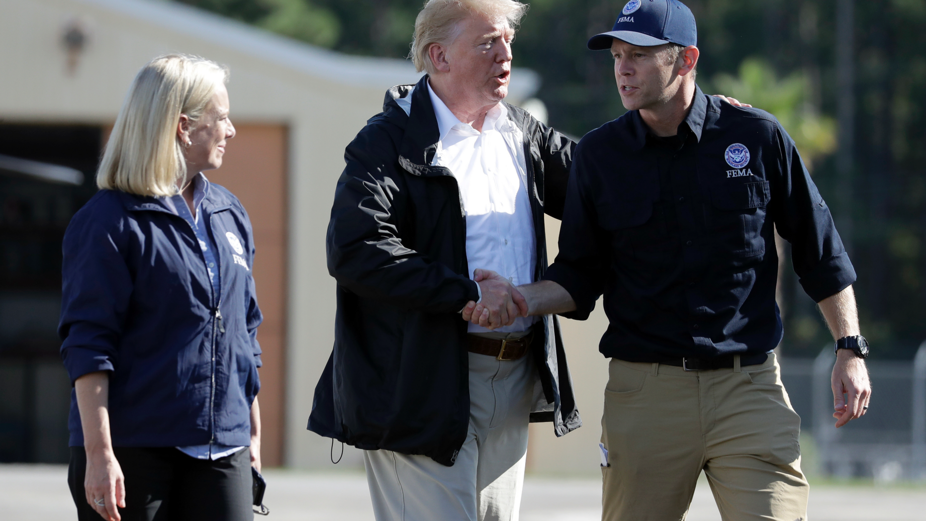 President Donald Trump shakes hands with FEMA Administrator Brock Long as Homeland Security Secretary Kirstjen Nielsen watches after visiting areas in North Carolina and South Carolina impacted by Hurricane Florence, Wednesday, Sept. 19, 2018, at Myrtle Beach International Airport in Myrtle Beach, S.C. (AP Photo/Evan Vucci)