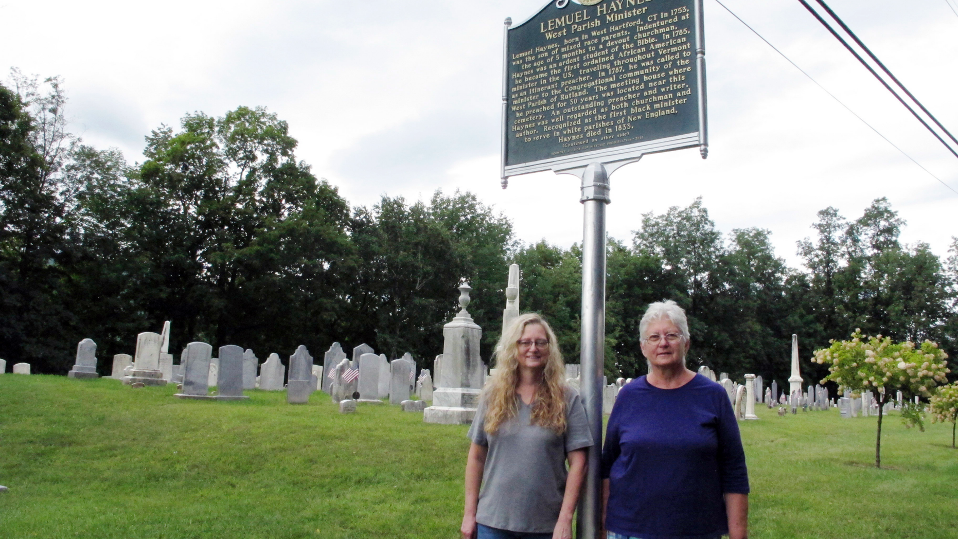 In this Sept. 6, 2018, photo, Michelle Jagodzinski, left, and Mary Reczek, right, of the West Rutland Historical Society in Vermont stand next to a new historical marker honoring Lemuel Haynes, first ordained black minister in the U.S. in West Rutland, Vt. (AP Photo/Lisa Rathke)