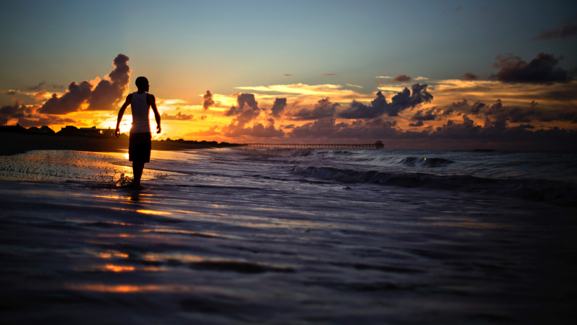 Andrew Lingle walks along the beach at sunrise as Hurricane Florence approaches the east coast in Atlantic Beach, N.C., Wednesday, Sept. 12, 2018. (AP Photo/David Goldman)