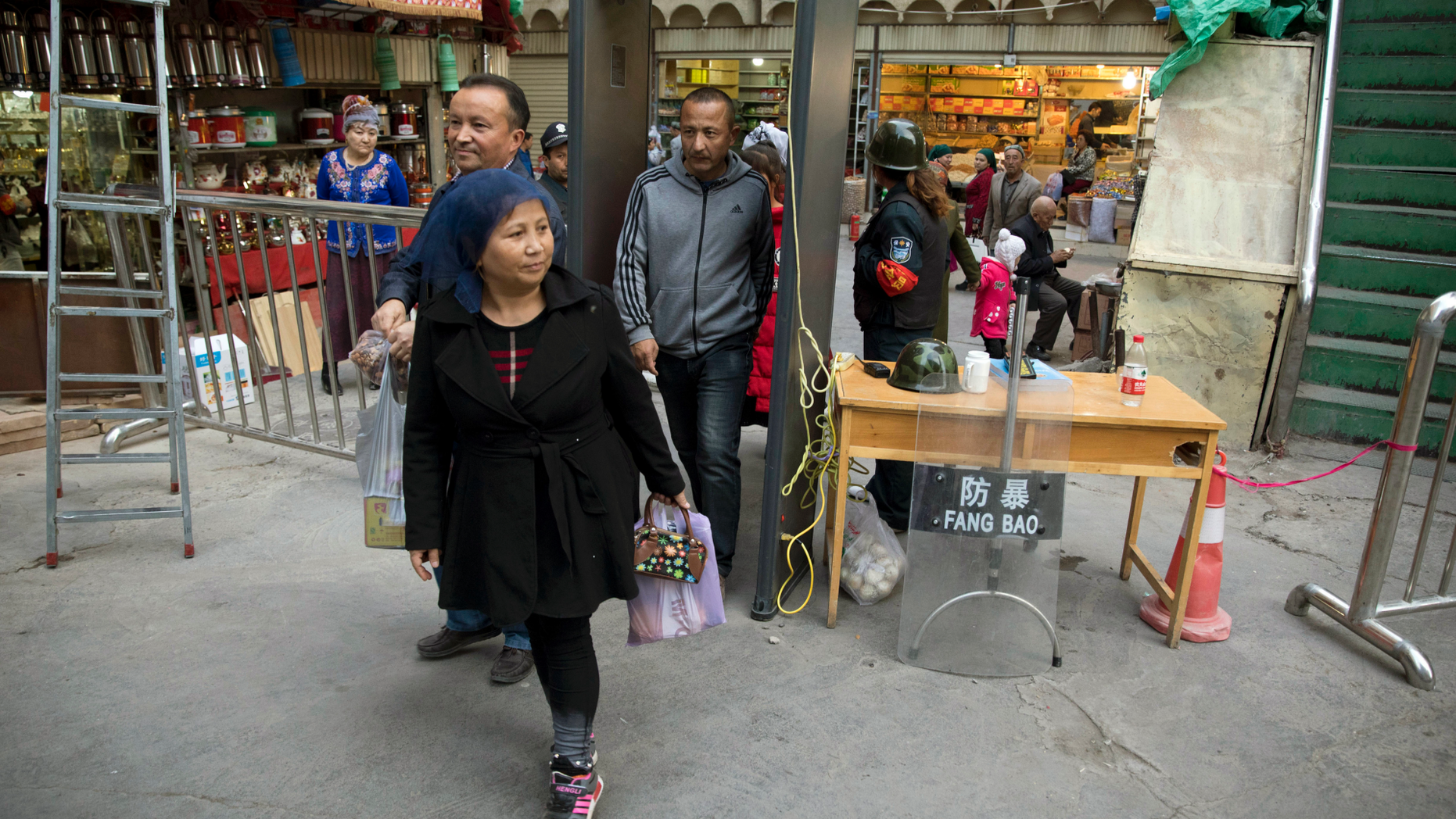FILE - In this Nov. 4, 2017 photo, residents past through one of the many security check points in Kashgar in western China's Xinjiang region. Two U.S. lawmakers are urging the extension of American export restrictions to prevent sales of equipment that could be used in China’s massive security clampdown targeting the Xinjiang region’s native Muslim population. Sen. Marco Rubio and Rep. Chris Smith said in a letter, Wednesday, Sept. 12, 2018, to the U.S. commerce secretary that they want foreign entities, including businesses, research institutions, government and private organizations, and individuals seen as profiting from the clampdown added to a watch list. (AP Photo/Ng Han Guan, File)