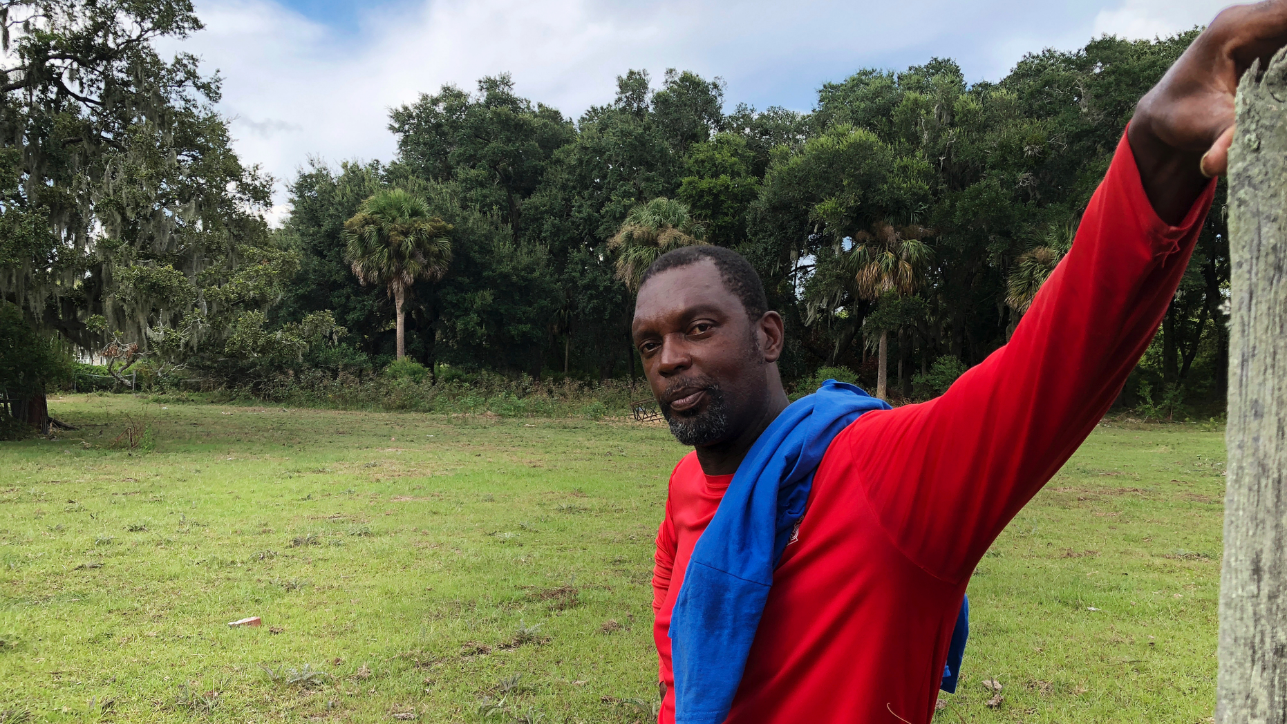 In this Sept. 11, 2018 photo, John Brown stands behind a fence for his cows outside his home on St. Helena Island, S.C. Brown and other residents of the island's Gullah community of slave descendants are watching Hurricane Florence as it approaches the Carolinas. St. Helena's Gullah residents have a long history of riding out storms, including a hurricane that killed an estimated 2,000 people in 1893. (AP Photo/Russ Bynum)