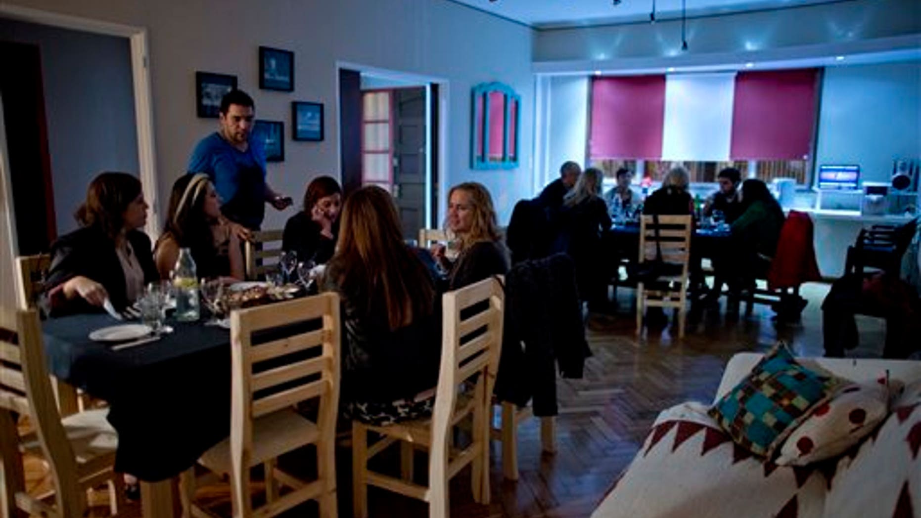 In this April 12, 2014, photo, Chef Ezequiel De La Torre, left top, talks to customers in Buenos Aires, Argentina. The website www.cookapp.com was launched in March 2013 and recently moved its headquarters from Buenos Aires to New York City. It works like a matchmaker, arranging intimate gourmet dinners between strangers. Chefs list when and where they will prepare particular meals; diners book what interests them, pay upfront via the app, then just show up and enjoy. (AP Photo/Natacha Pisarenko)