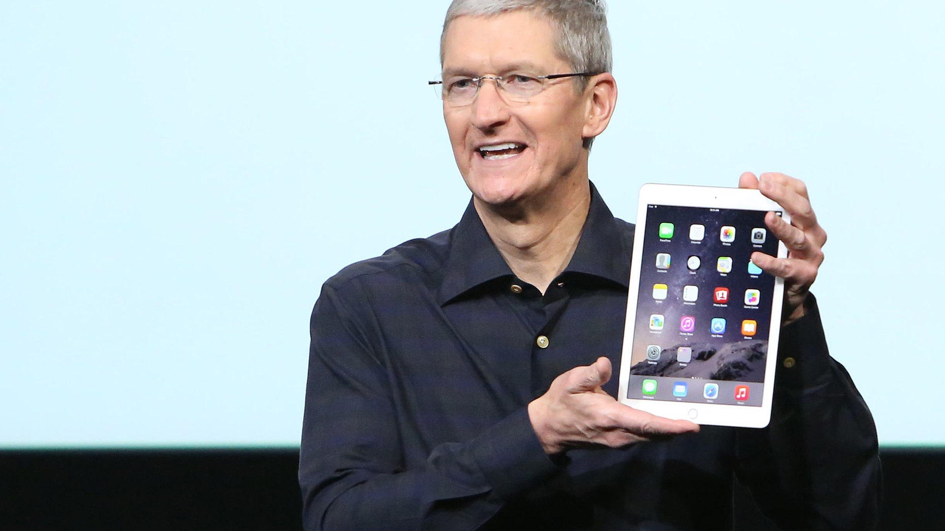 Apple CEO Tim Cook holds an iPad during a presentation at Apple headquarters October 16, 2014.