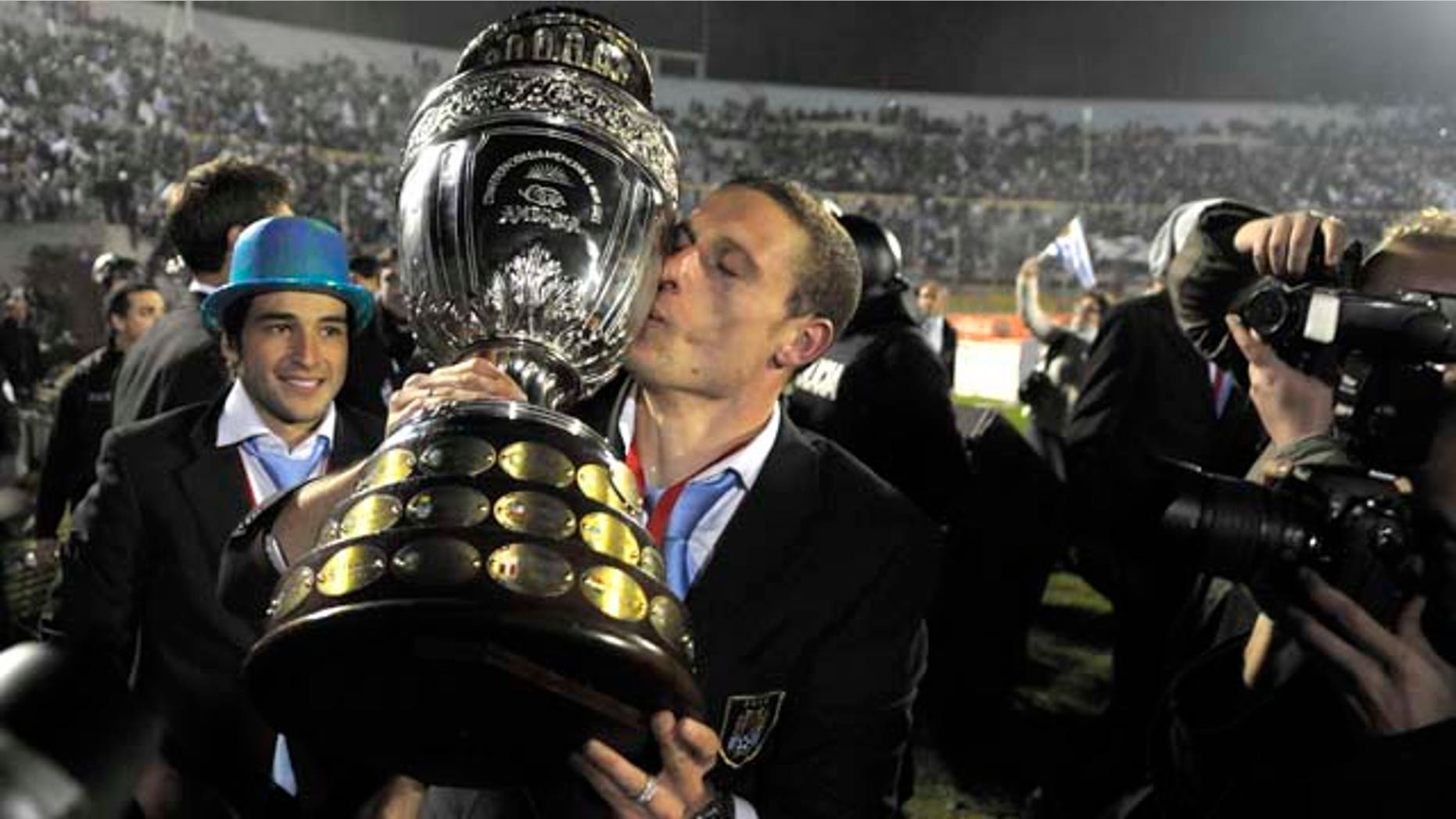 Uruguay's Diego Perez kisses the trophy as the team celebrates in the Centenario Stadium in Montevideo, Uruguay Monday July 25, 2011. Uruguay won the Copa America for a record 15th time after beating Paraguay 3-0 in Argentina Sunday. (AP Photo/Andres Cuenca) (AP Photo/Matilde Campodonico)