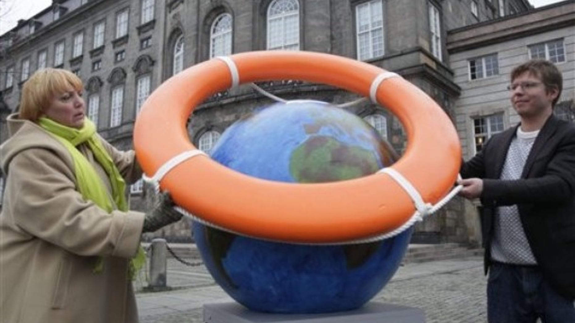 Claudia Roth, left, leader of the German Green Party, and Jakob Norhoj, right, of the Danish Socialist people's party, put a lifebuoy around planet earth outside parliament, rear, in Copenhagen Friday Dec. 11, 2009.