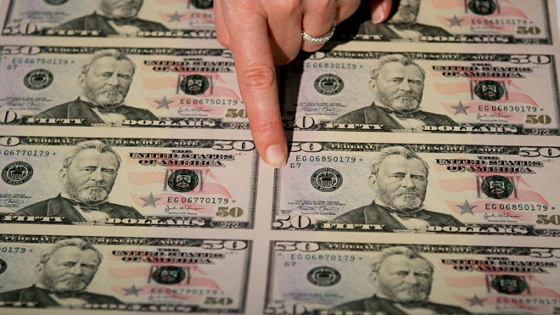WASHINGTON - SEPTEMBER 28: Julie Borchard of the U.S. Treasury Department points out new improvements on the newly unveiled fifity dollar bill September 28, 2004 in Washington, DC. The newly redesigned bill, with a "Stars and Stripes" design theme, was released into circulation today. (Photo by Mark Wilson/Getty Images)
