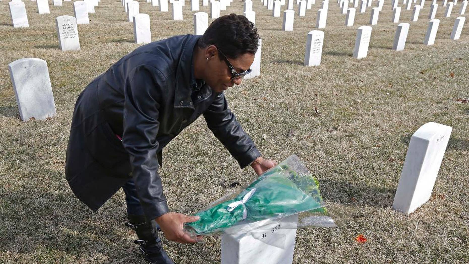 Dellaina Grundy places flowers on her father's headstone, Army veteran Leroy Metcalfe, Saturday, March 8, 2014, at the Dayton National Cemetery in Dayton, Ohio. Grundy isn’t sure whether any or all of the cremated remains buried in the grave are his and knows that mystery will never be solved.(AP Photo/Al Behrman)