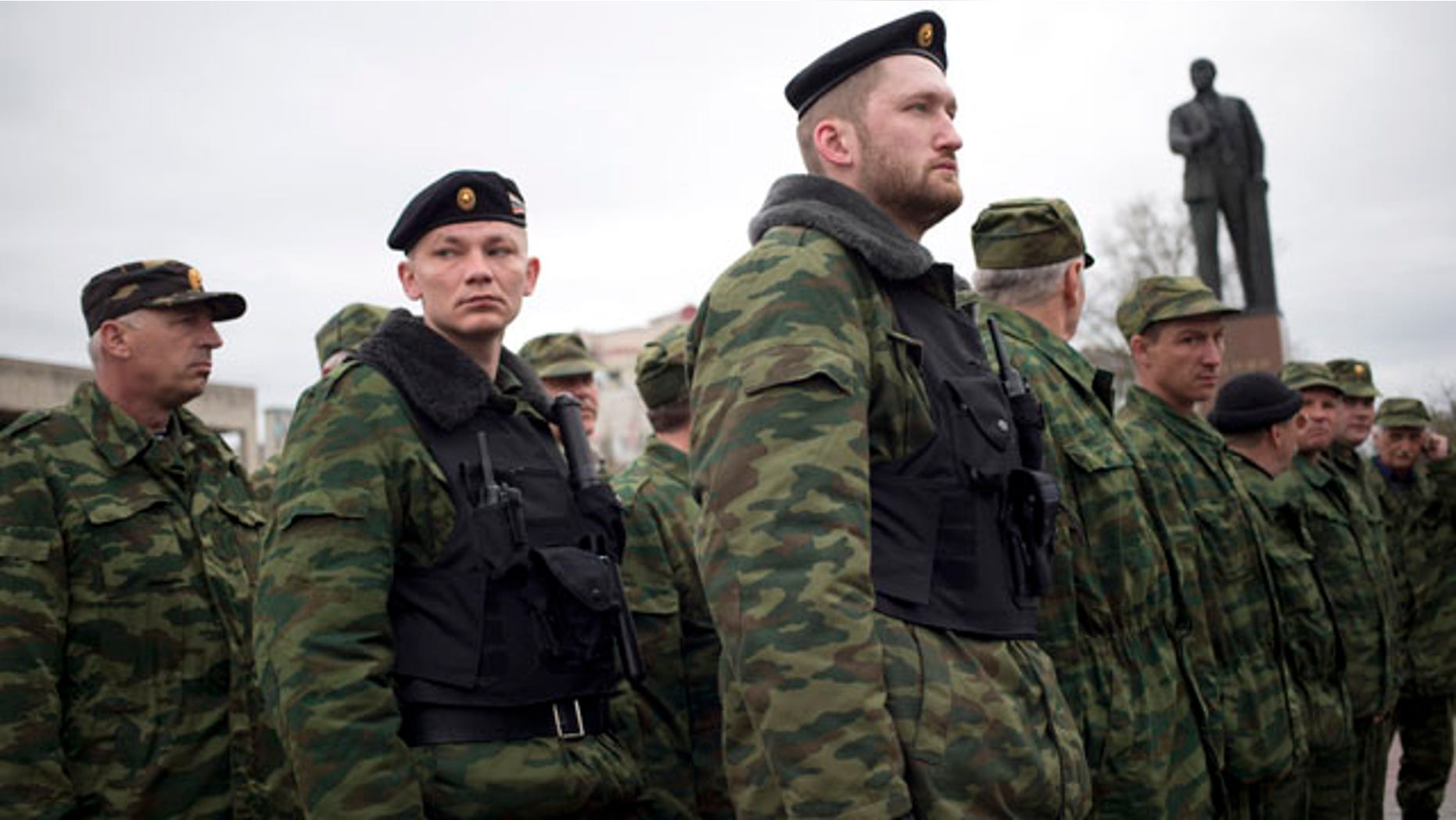 March 27, 2014: Members of the Crimean self defense forces gather for their morning briefing prior to patrolling the city at Soviet Union founder Vladimir Lenin's statue in Simferopol, Crimea. Crimea's government has decided to disband self-defense forces which provided help to the Russian military which have been occupying since late February. (AP Photo/Pavel Golovkin)