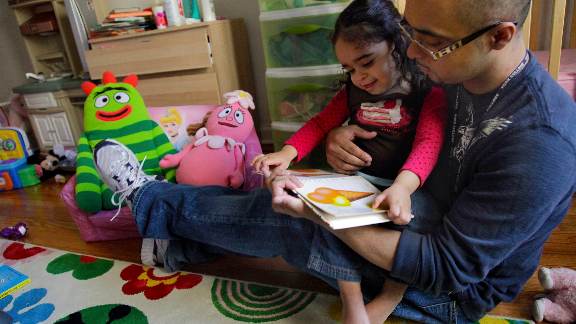 Christopher Astacio reads with his daughter Cristina, 2, recently diagnosed with a mild form of autism. (AP Photo/Bebeto Matthews)