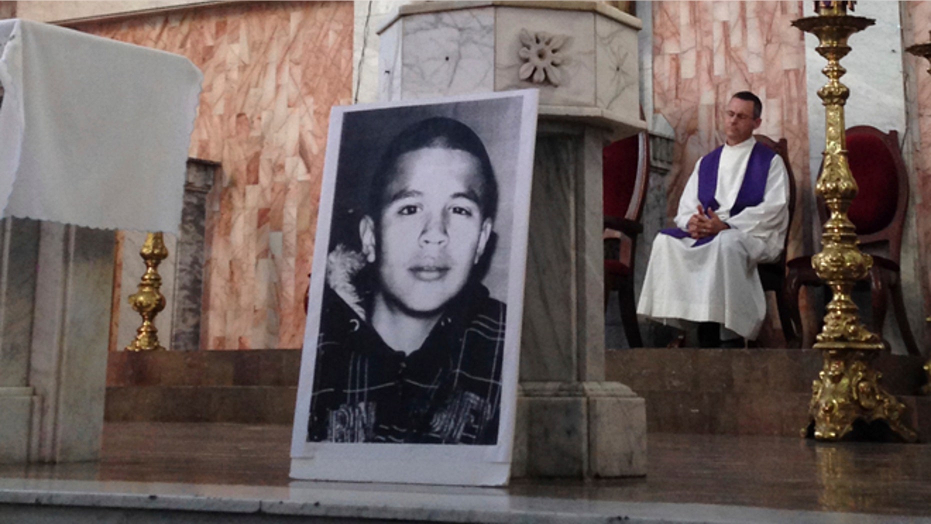 FILE - In this Oct. 14, 2014, file photo, a photo of Jose Antonio Elena Rodriguez, who was fatally shot by U.S. Border Patrol near the Mexico-U.S border, leans against a podium on a church altar during a memorial mass in Nogales, Sonora, Mexico. The civil rights case against Agent Lonnie Swartz over the Rodriguez' death will go forward after U.S. District Court Judge Raner C. Collins denied a part of his motion to dismiss the case. (AP Photo/Valeria Fernandez, File)