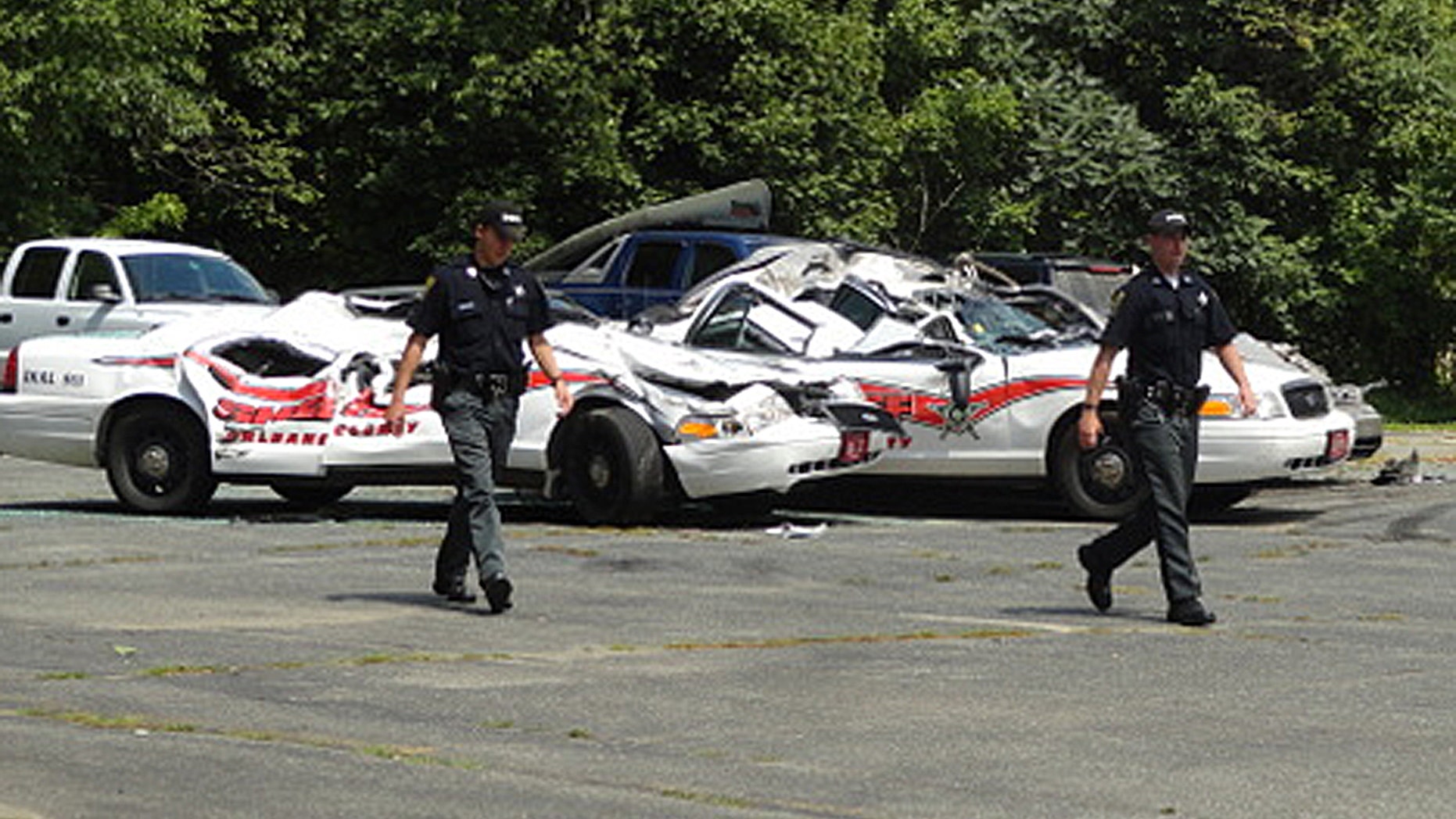 Aug. 2, 2012: Sheriff officers walk past crushed cruisers at the Orleans County Sheriff's Department in Newport, Vt.