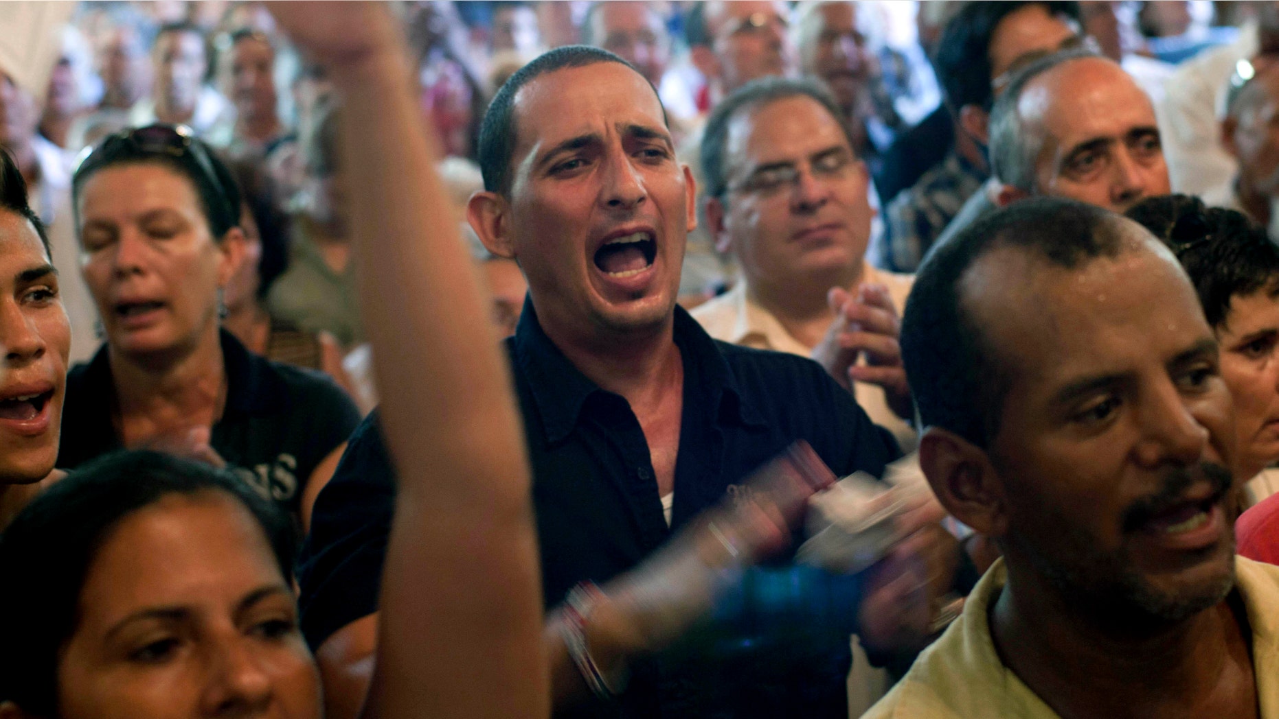 Mourners shout opposition slogans during a funeral mass honoring the Cuban activist Oswaldo Paya in Havana, Cuba, Monday, July 23, 2012. Paya, who spent decades speaking out against the communist government of Fidel and Raul Castro and became one of the most powerful voices of dissent against their half-century rule, died Sunday in a car crash. He was 60. (AP Photo/Ramon Espinosa)